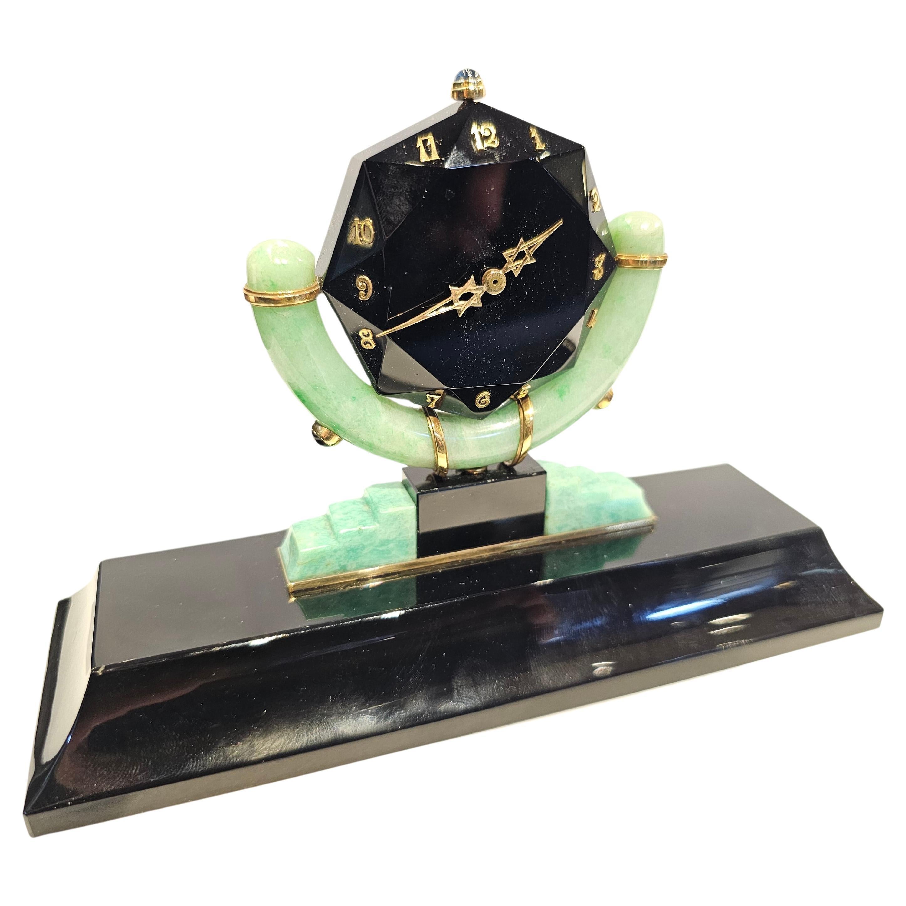 Art-déco-Schreibtischuhr von Rene Boivin aus Onyx, Jade und Amazonit

Diese äußerst seltene Uhr hat ein Zifferblatt aus Onyx mit goldenen Ziffern und Zeigern, die von einem Cabochon-Saphir gekrönt werden, der auf einem Onyx-Sockel steht, der mit