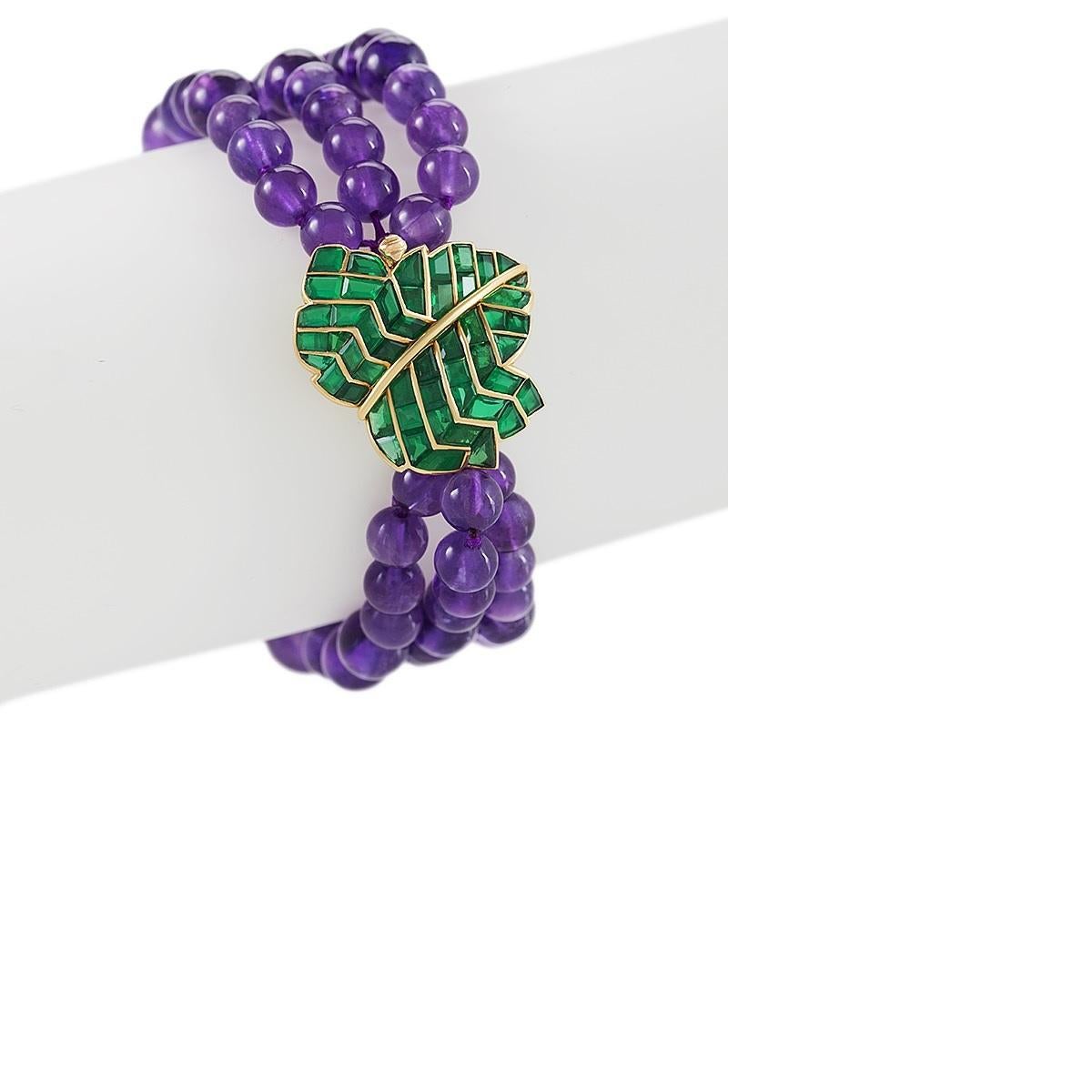 A French-Mid 20th Century18 karat gold bracelet with amethyst and emerald by René Boivin. The bracelet is composed of  66 graduated amethyst beads measuring 10.00 mm to 6.0 mm. The leaf clasp has 50 calibre cut emeralds with an approximate total
