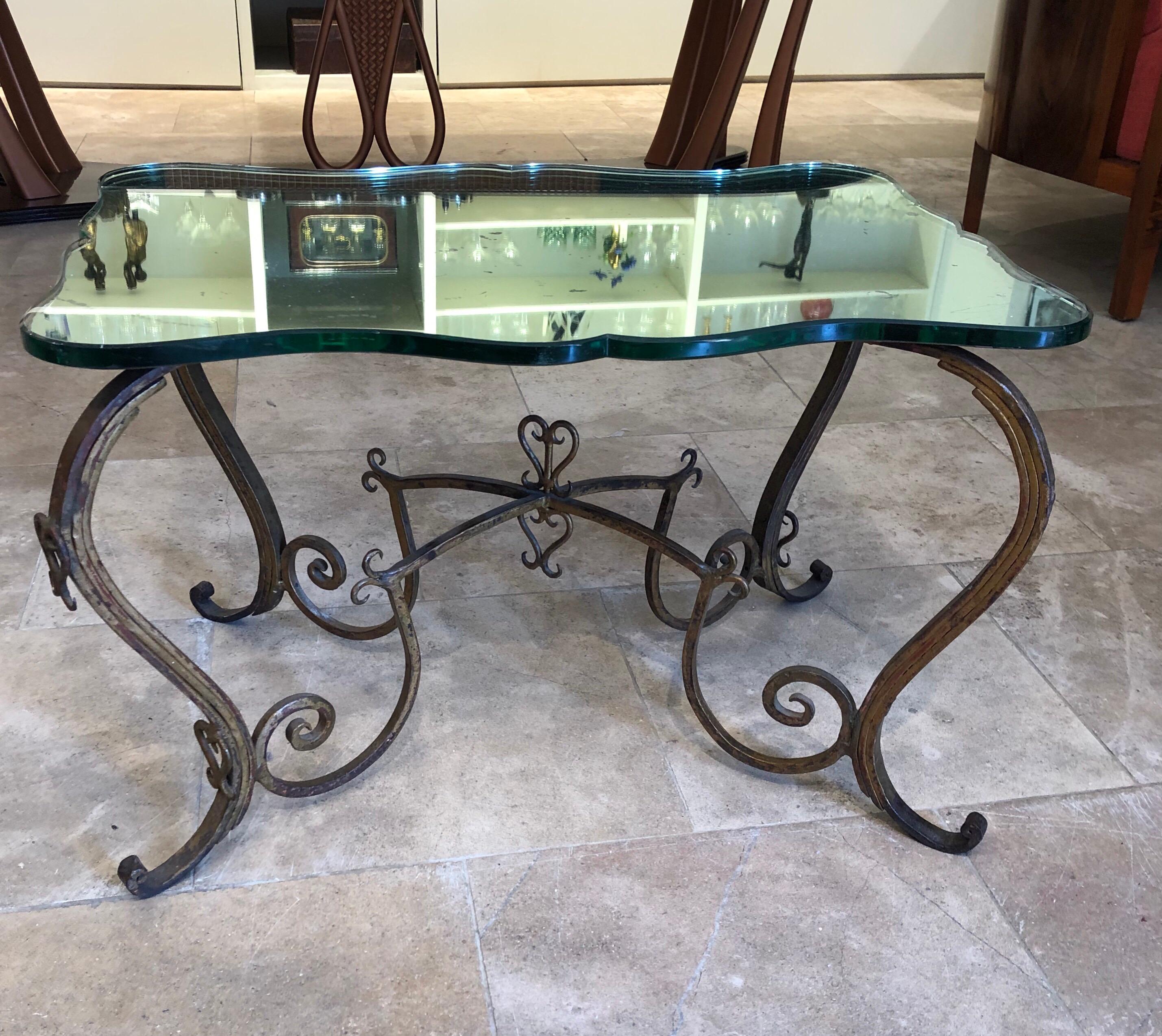 A beautiful hand forged gilded metal table with original curved glass mirrored top attributed to Rene Drouet. The mirrored top has some imperfections due to age but this adds to the beauty.