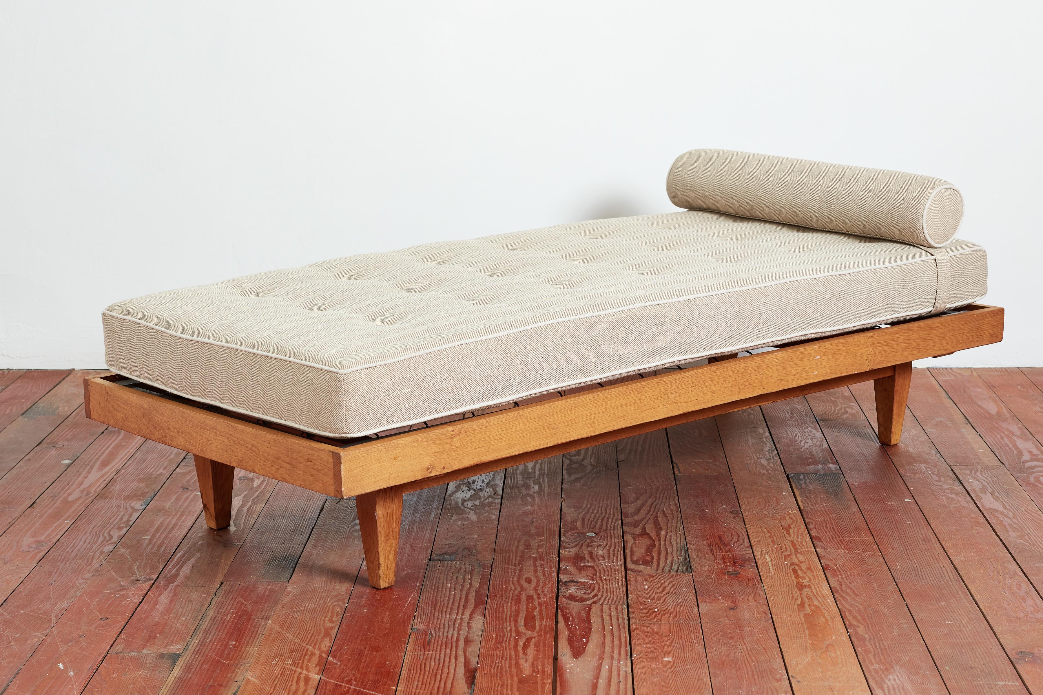 1950's French daybed with sleek oak wood frame by Rene Gabriel 

Clean oak frame with original metal spring mattress and new cushion upholstered in herringbone linen with natural linen piping on bolster and seat. 

Wonderful patina to oak and great