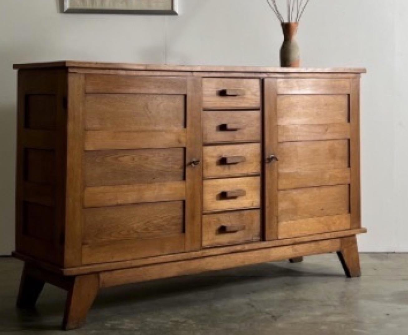 French reconstruction period oak sideboard by Rene Gabriel. A handsome piece with great simple lines and exceptional storage capacity. A central column of five wood drawers with wood block handles is flanked by two paneled cabinet doors, giving the