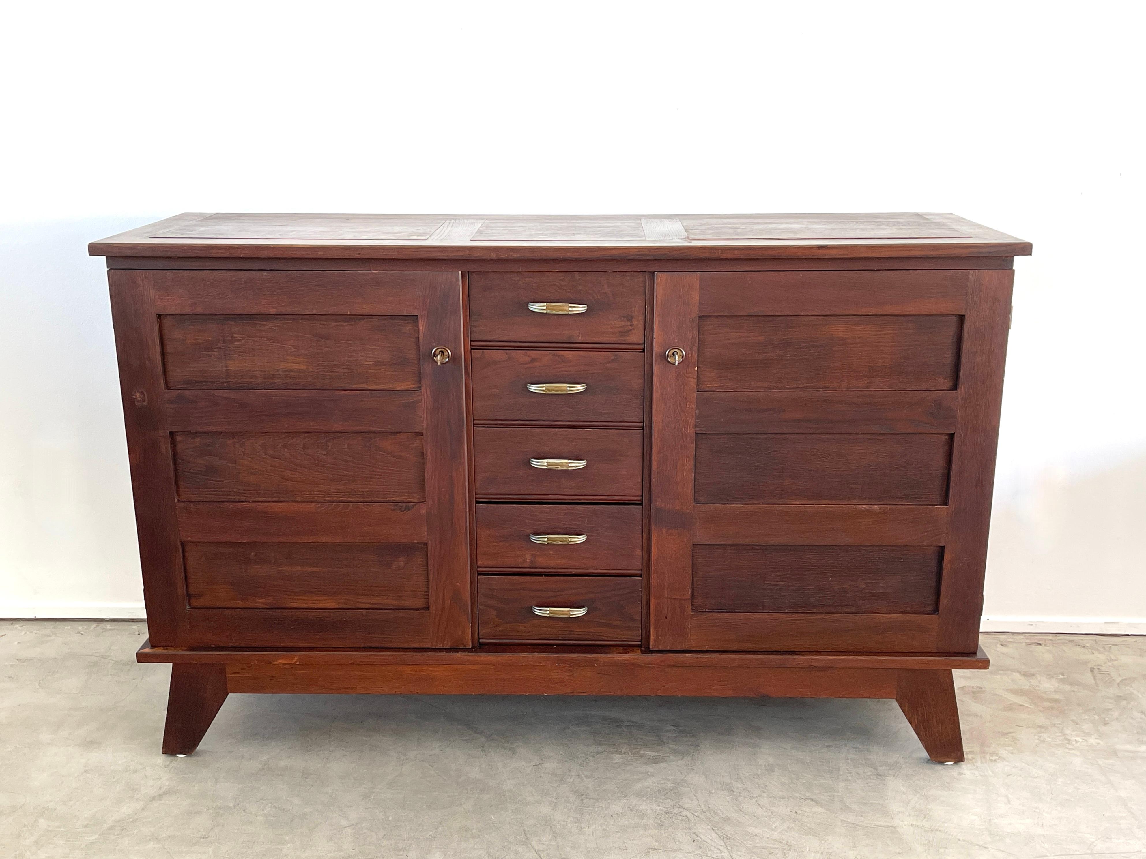 Gorgeous sideboard by Rene Gabriel with great angled lines and wood patina
Cabinet has 2 swinging doors with 5 center drawers and brass handles.
Great piece.