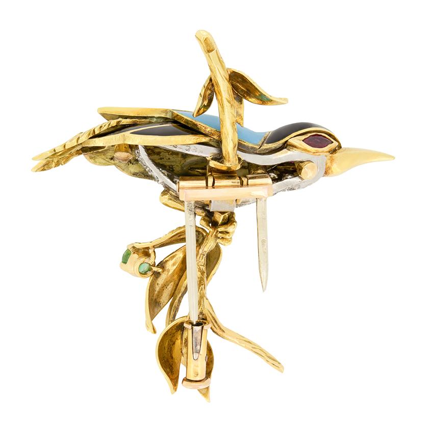 Diese wunderschöne Brosche von René Kern hat die Form eines Vogels, der auf einem Ast sitzt. Der aus 18 Karat Gelbgold gefertigte Vogel wird durch farbige Emaillierungen auf den Flügeln und dem Kopf sowie durch Diamanten auf der Brust zum Leben