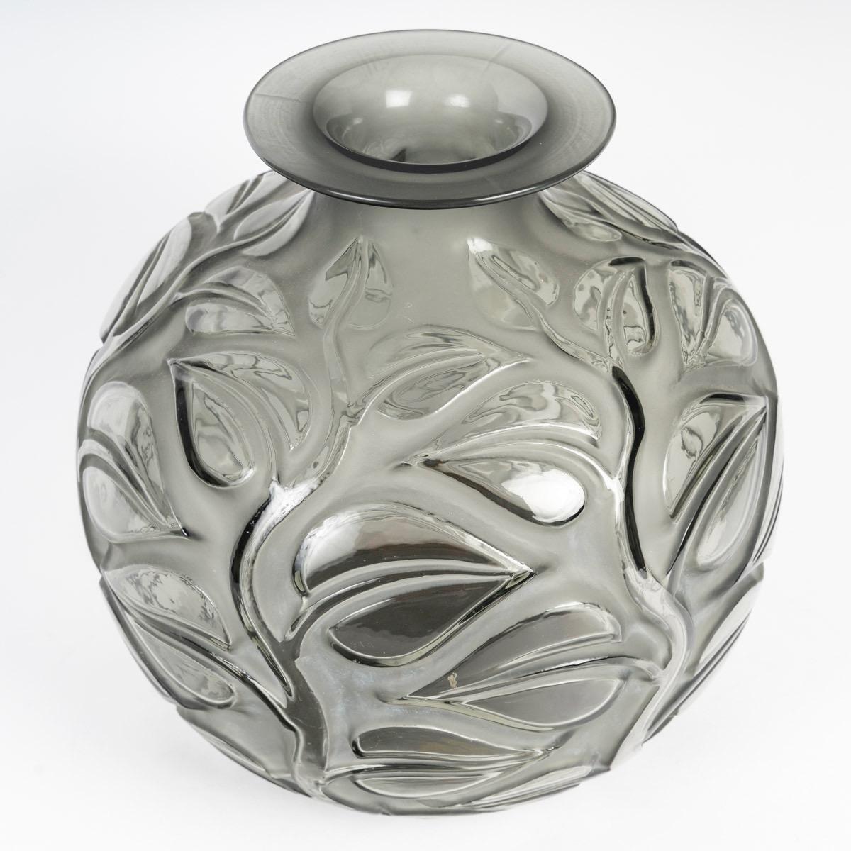 René Lalique (1860-1945) Jarrón Sophora 1926

Jarrón de vidrio soplado gris Sophora
Diseñado con hojas y ramas en altorrelieve.
El color no es una mancha externa. Está dentro del propio cristal, teñido de gris en la masa.
Firma moldeada R.LALIQUE