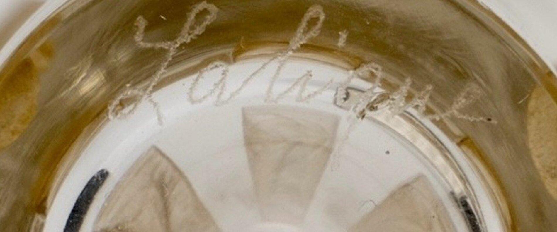 Set of 6 goblets with title motifs in vertical reserves. Pressed-molded glass proofs (ref. Marcilhac 3400), enhanced with an original sienna patina.

created in [1911], not reproduced after 1947 
(ref. Marcilhac 3400 page 768).
The suite is