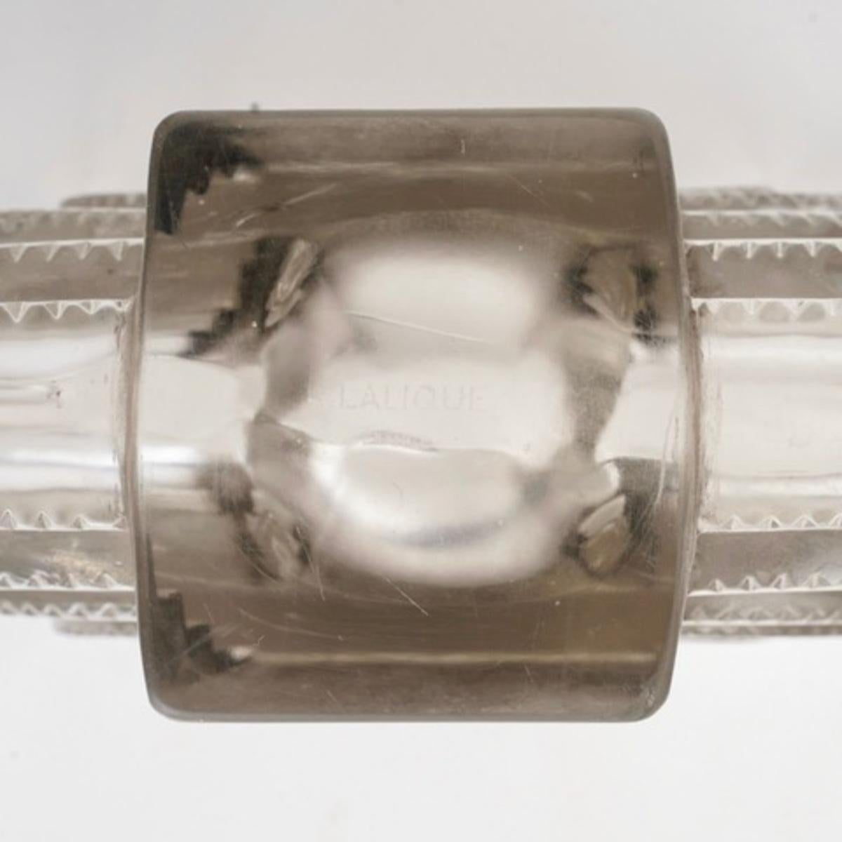 Vase en verre moulé pressé avec un motif sablé sur la partie centrale.
 Verre blanc rehaussé d'une patine grise. Créée par René Lalique en 1936.
Signature sablée. 

Parfait état. 

hauteur : 18.5 cm 
longueur : 30 cm 

Bibliographie : Félix