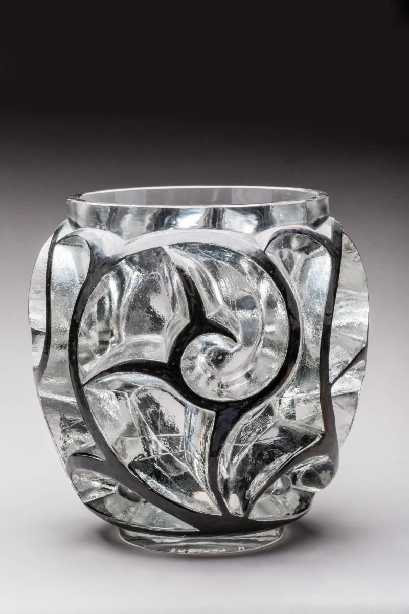 Clear and frosted thickly molded glass with a high relief stylized whirlwinds molded design all-over the exterior highlighted by black enamel
Model created in 1926.
Bibliographie : Félix Marcilhac, 