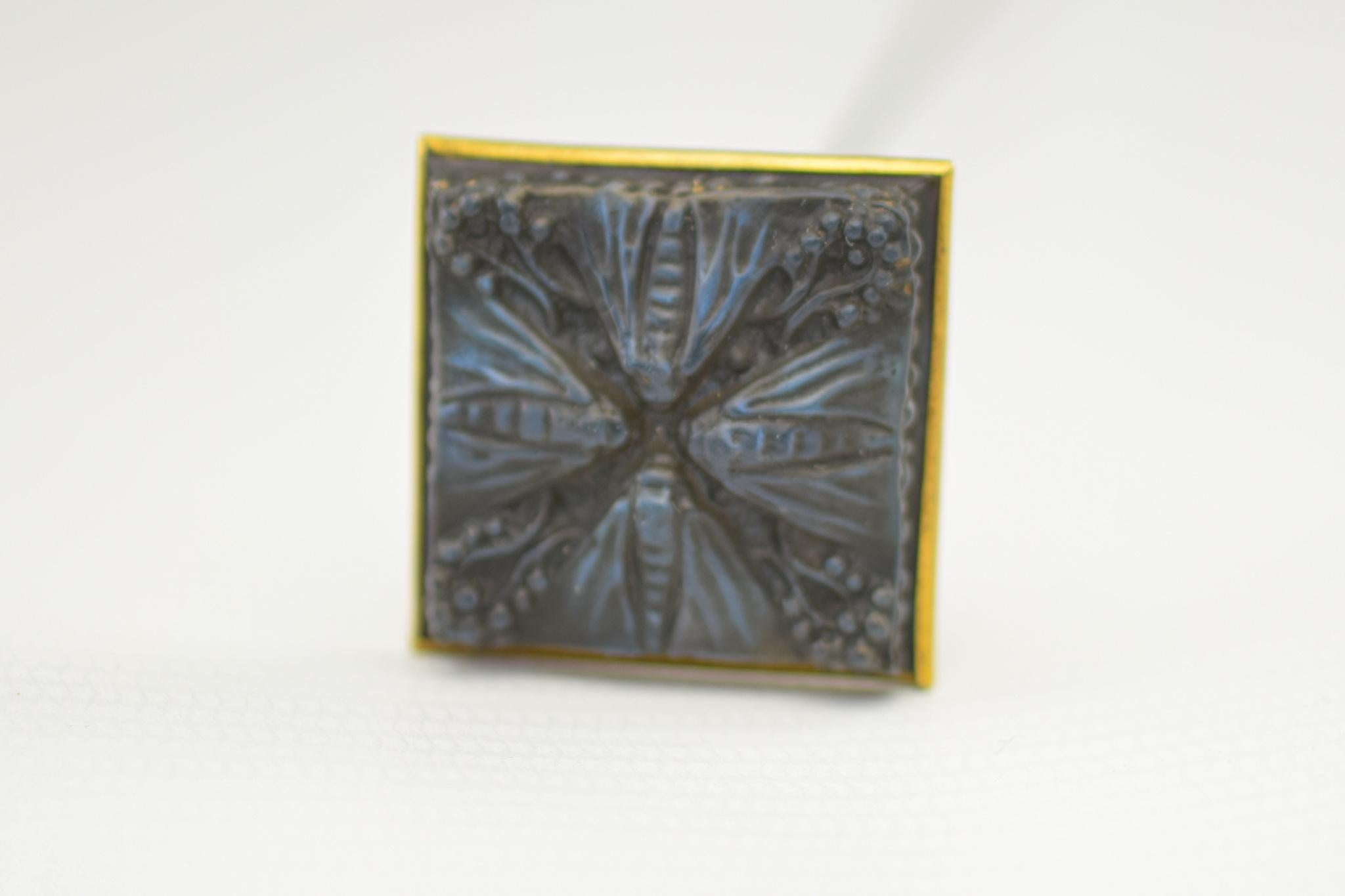 Rare quatre papillons hatpin. Blue foil backed clear and frosted glass highlighted with black staining. The brass back is stamped Lalique along with the RL stamp

The condition is very good, with no damage.
The steel pin is tarnished and show signs