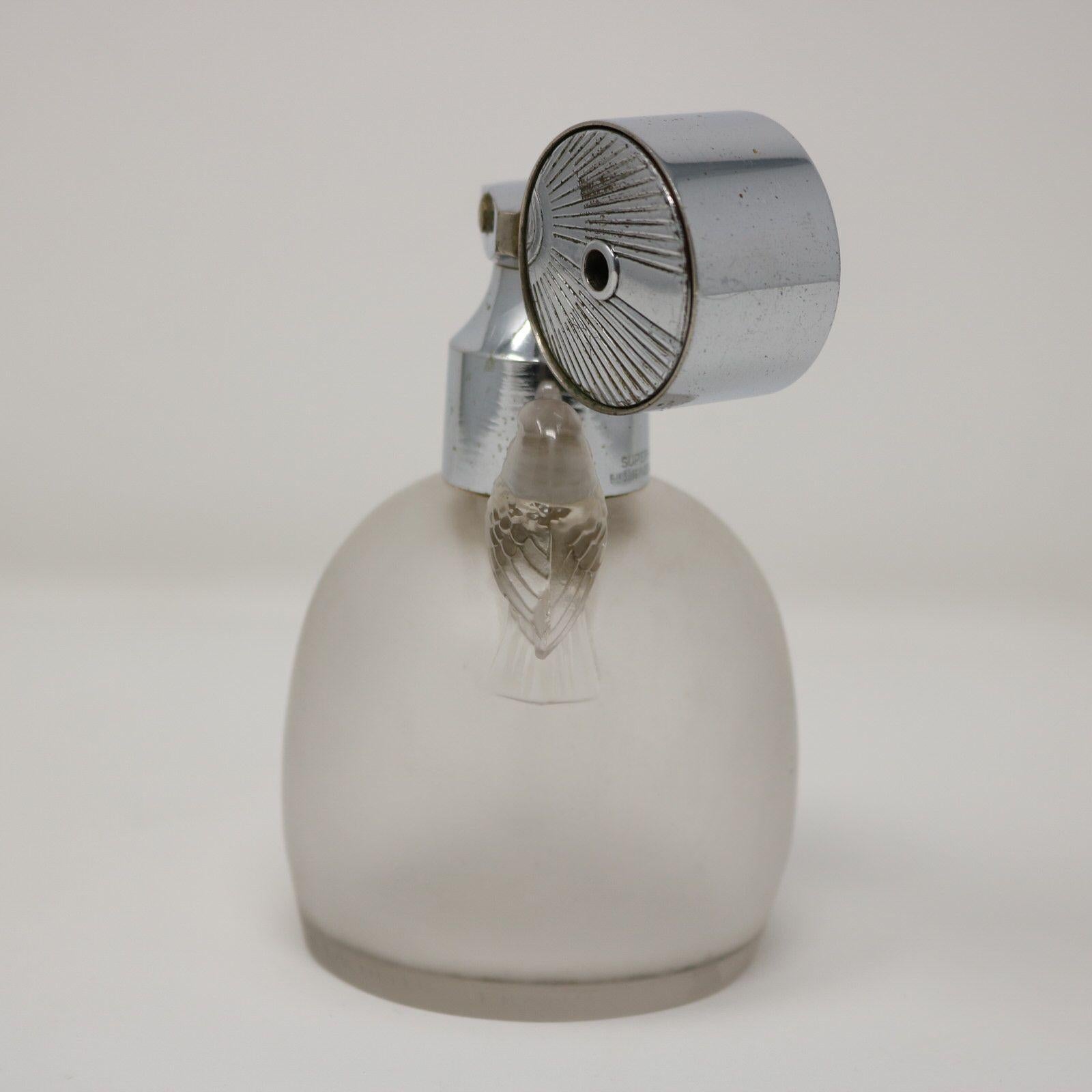 Flacon de parfum 'Marcel Frank Perruches' en verre dépoli de René Lalique avec vaporisateur. Ce motif représente deux oiseaux, assis de part et d'autre du goulot de la bouteille. Marque du fabricant, 'R LALIQUE FRANCE', autour de la base. Référence