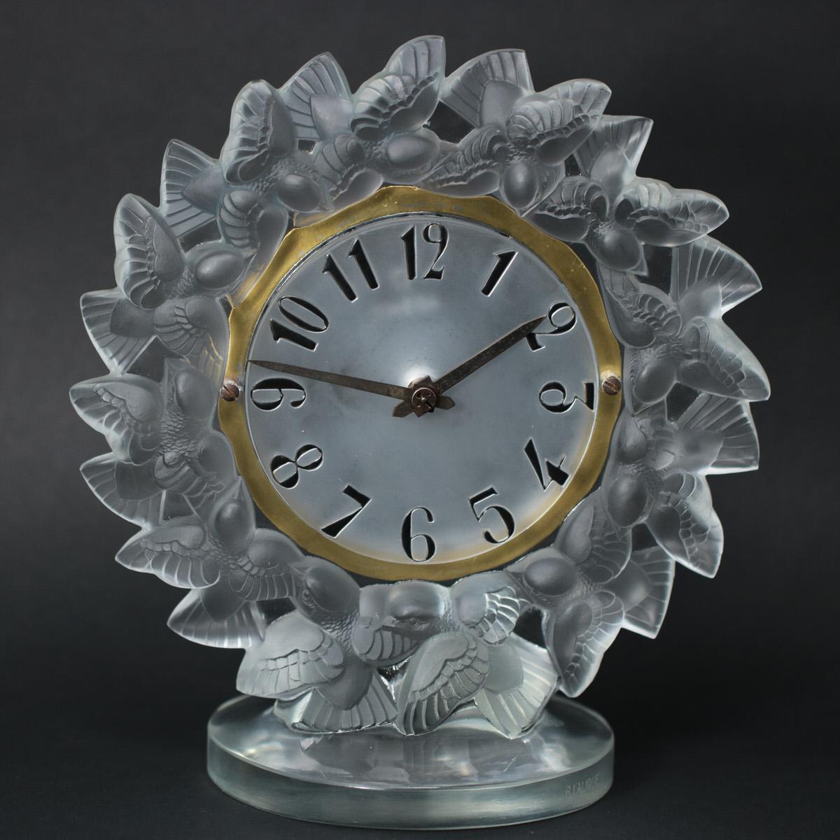 René Lalique Uhr 'Roitelets' aus mattiertem Glas. Dieses Design zeigt einen Ring von fliegenden Vögeln (Zaunkönigen) um das Zifferblatt. Die Ziffern auf dem Ziffernblatt sind aus Glas geformt und mit schwarzer Emaille bemalt. Eingravierte
