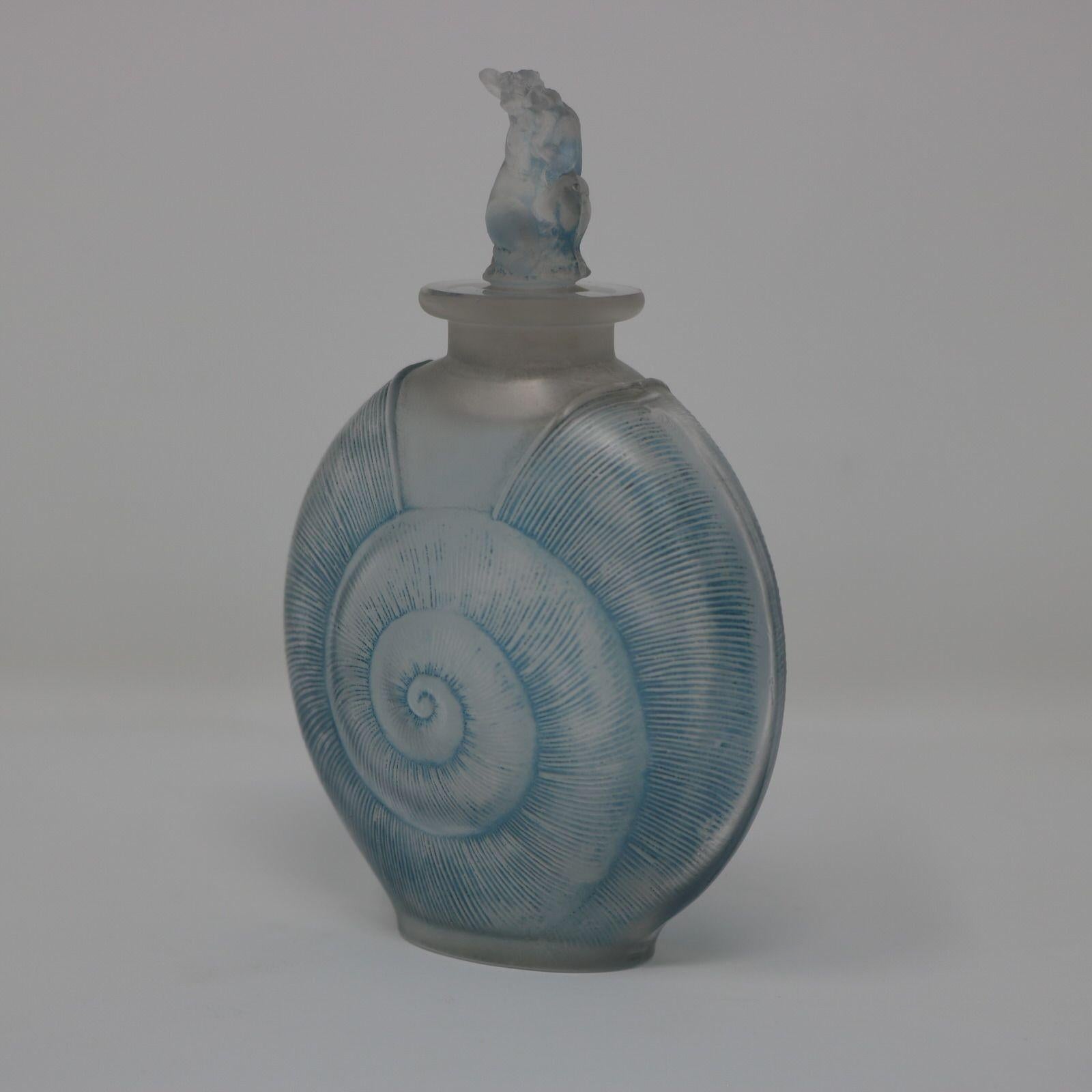 Rene Lalique frosted glass with blue staining 'Amphitrite' Perfume bottle. The bottle is molded in the form of a shell. The stopper has a naked female in a crouching pose. She represents the greek goddess Amphitrite. In ancient Greek mythology,