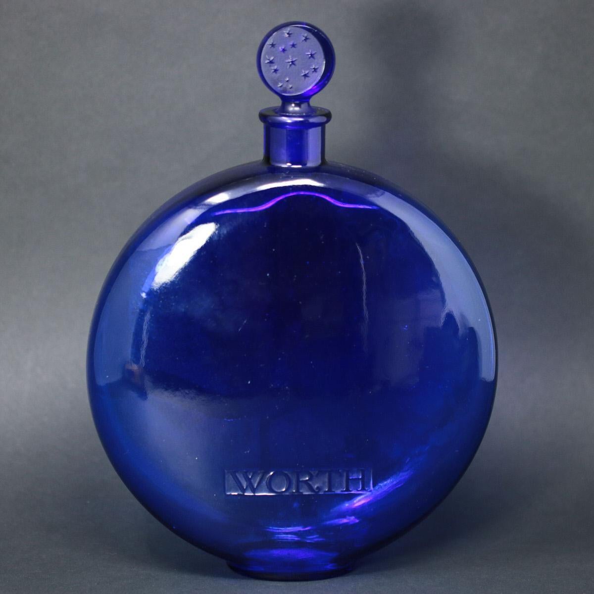 Rene Lalique blue, clear glass 'Dans La Nuit' perfume bottle. Stars and moon stopper. Moulded perfume maker mark, 'WORTH', to the side. Moulded makers mark, 'R. LALIQUE', to the underside. Engraved number, '688' (?) to the underside. Book reference: