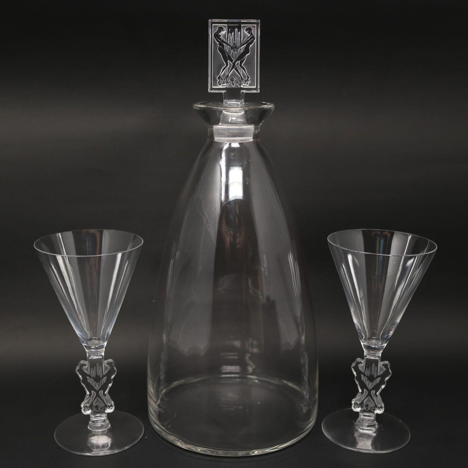 Rene Lalique glass 'Strasbourg' Decanter with two matching glasses. The rectangular shaped stopper features two men grape stomping. The stems of the glasses feature the same motif. Makers mark, 'R LALIQUE FRANCE' stencilled onto the underside of the