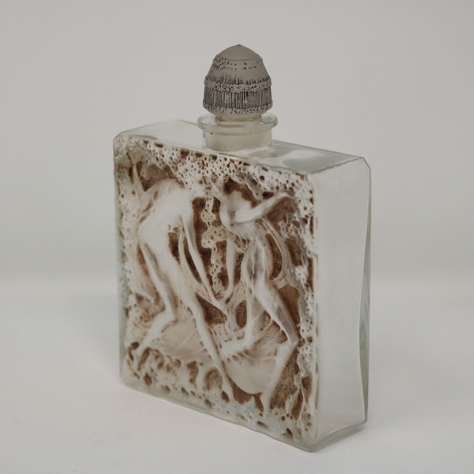 Rene lalique clear and frosted glass L'elegance perfume bottle. This pattern features two dancing female figures amongst flowers. Sepia stained relief details. An original paper label for 'L'ELEGANCE D'ORSAY' to the side. Inscribed mark to the