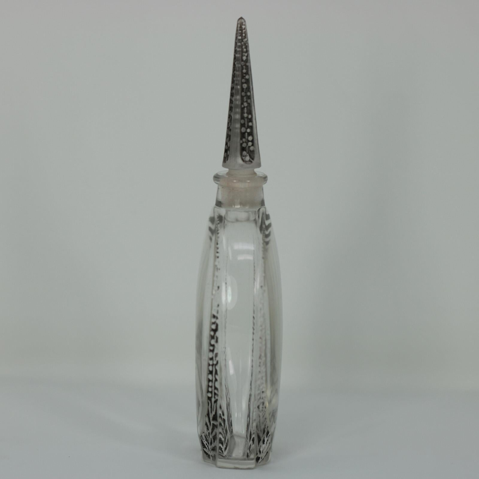 René Lalique clear glass, black patinated perfume bottle. 'Sur Deux Notes' design. This design features flowers rising up the sides of the bottle and a striking stopper in the shape of an enlongated pyramid. Moulded makers mark, 'LALIQUE'. Engraved