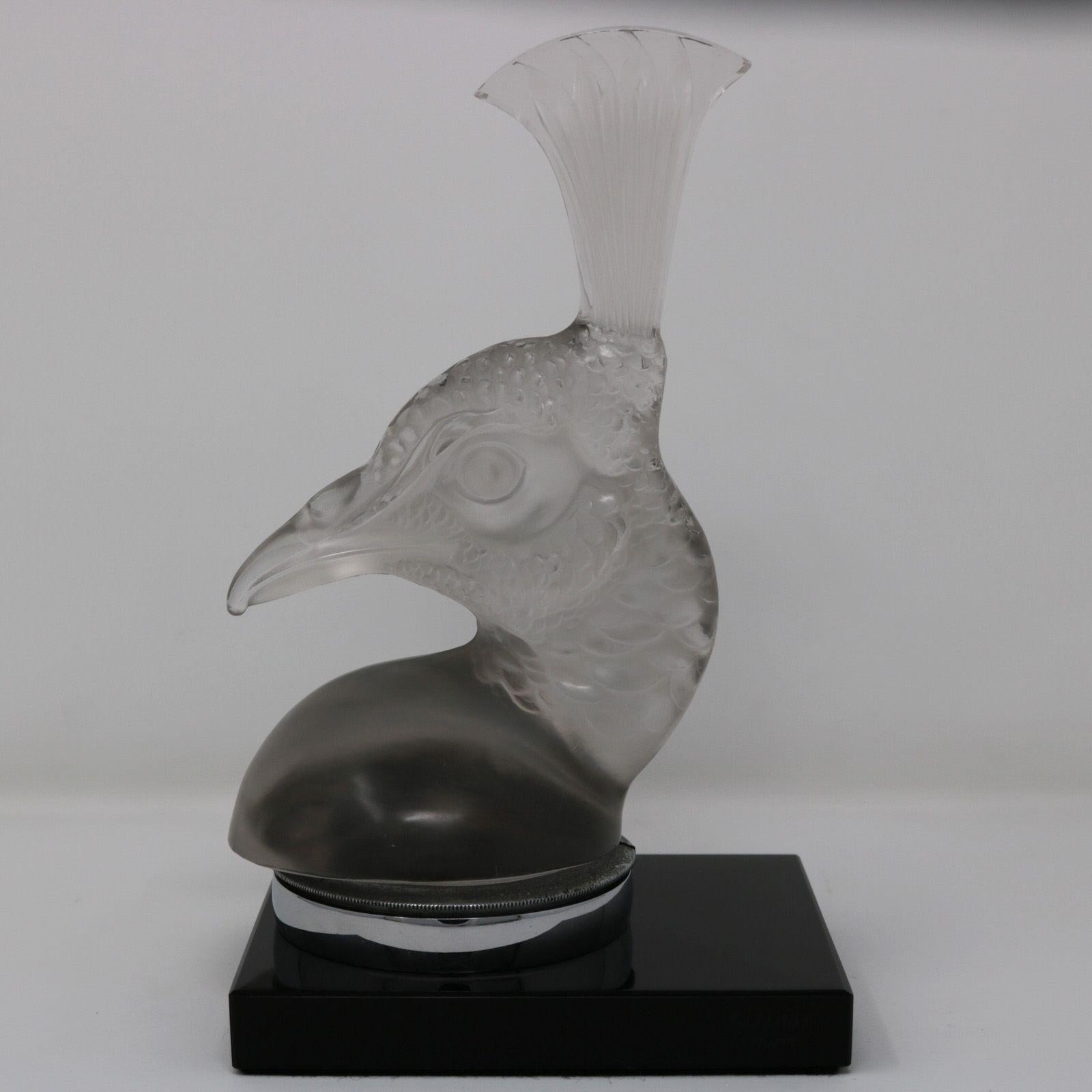 Mascotte de voiture 'Tete De Paon' en verre clair et dépoli de René Lalique. Ce modèle présente la tête d'un paon. L'oiseau est monté sur une base rectangulaire en verre noir. Marque de fabricant moulée sur le bord de la base, 