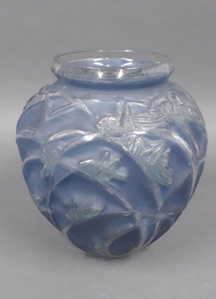 René LALIQUE (1860 - 1945) Sauterelles vase, created in 1912. Moulded white blown glass with blue patina. Signed at the point on the reverse.
 H. 27.5 cm
 History: included in the 1928 catalog, removed from the catalog in 1932 and not included after
