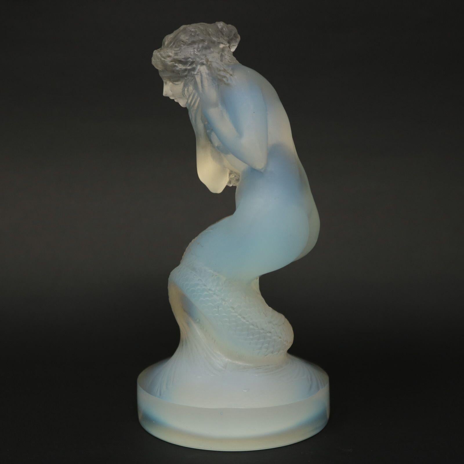 Rene lalique opalescent glass 'naiade' statuette. Grey stained details. Features a naiad crouching, holding a shell(?) up to her ear. In Greek mythology, the naiads are a type of female spirit or nymph, with fish tails. They preside over wells,