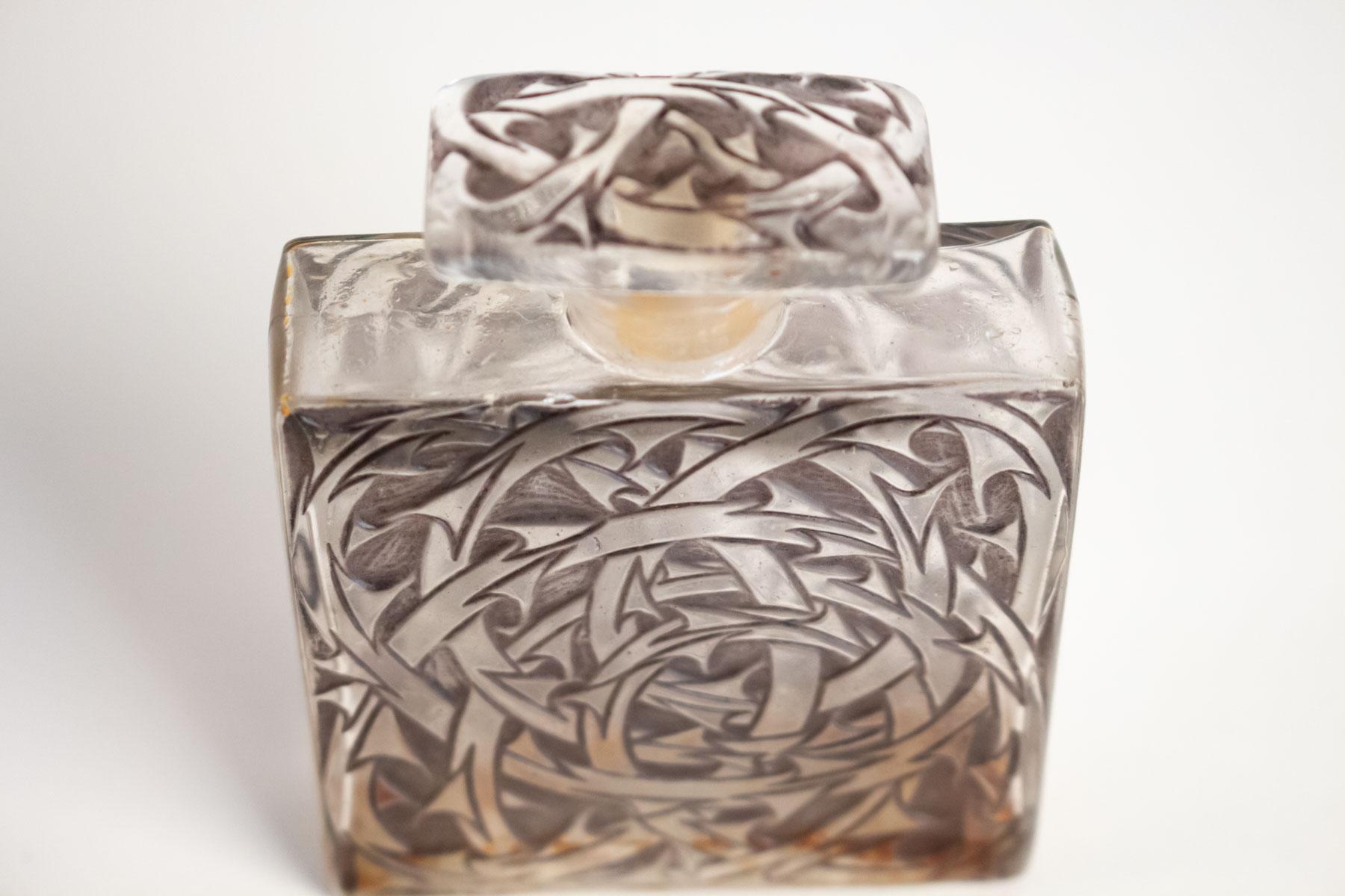Rene Lalique Perfume Bottle Entrelacs:
Model: Volnay-Perfume-7, circa 1921.
Glass container under a rectangular stopper with both parts decorated with a molded briar pattern
8.5 centimeters tall with matching vine design all-over the body and