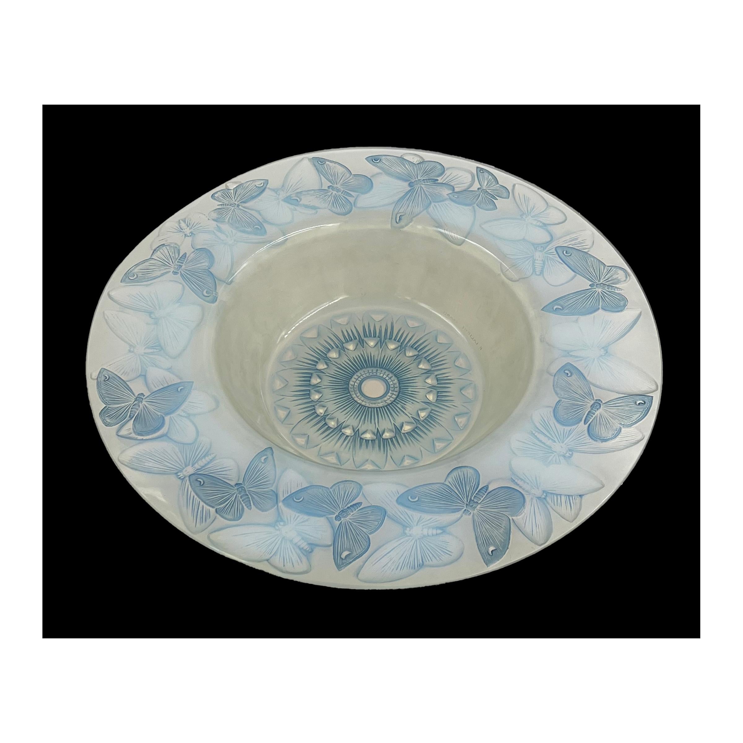 Immerse yourself in the timeless beauty of this 1929-designed Phalenes Bowl by Rene Lalique. Measuring 39 cm wide, the opalescent and blue stained glass showcases a mesmerising interplay of relief and intaglio moulded butterfly, skilfully creating a