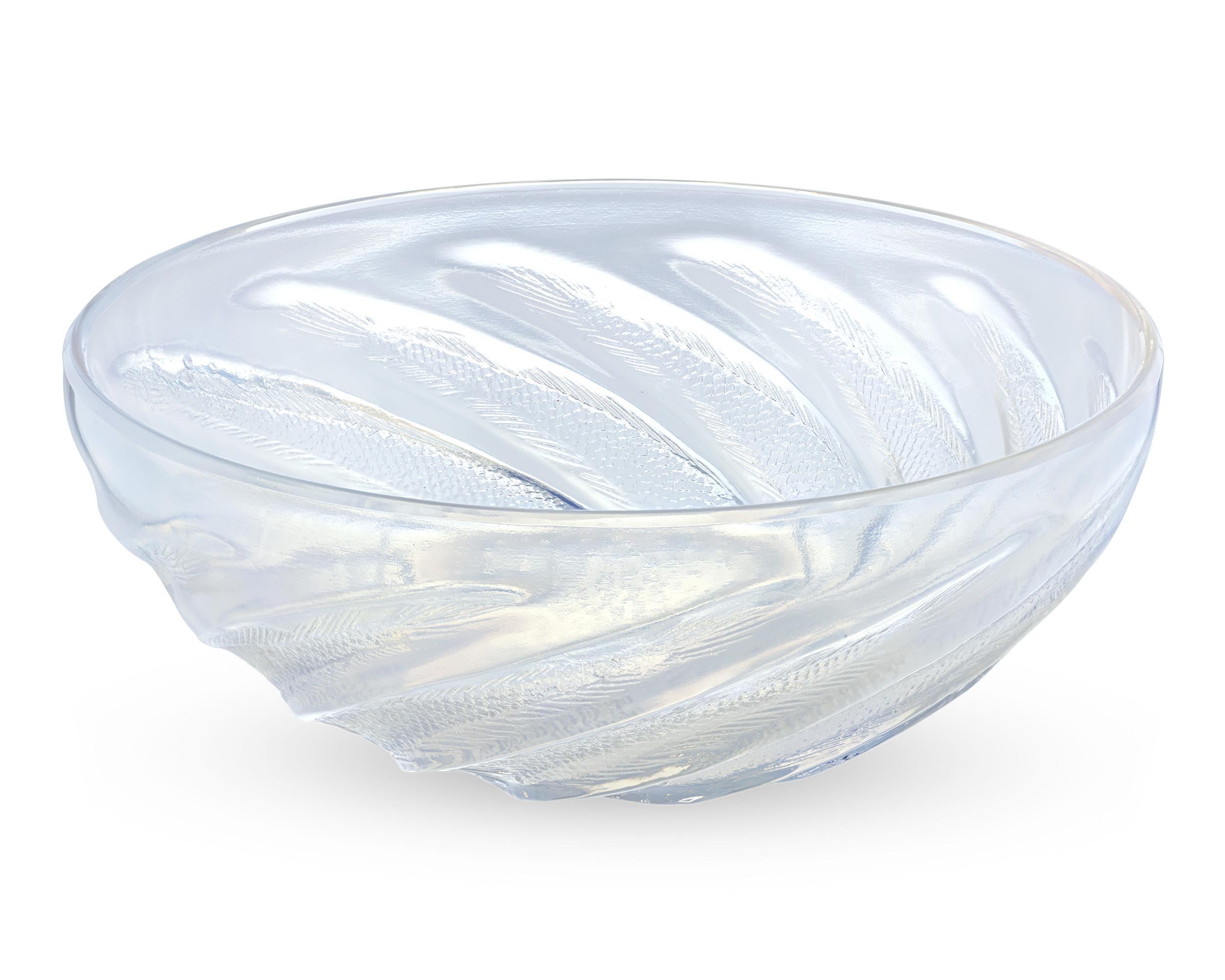 Designed by René Lalique in 1921, this Poissons pattern bowl showcases a swirling motif composed of lithe swimming fish. The vessel highlights the master's love of the bold forms and the natural motifs that typified his output. Composed of