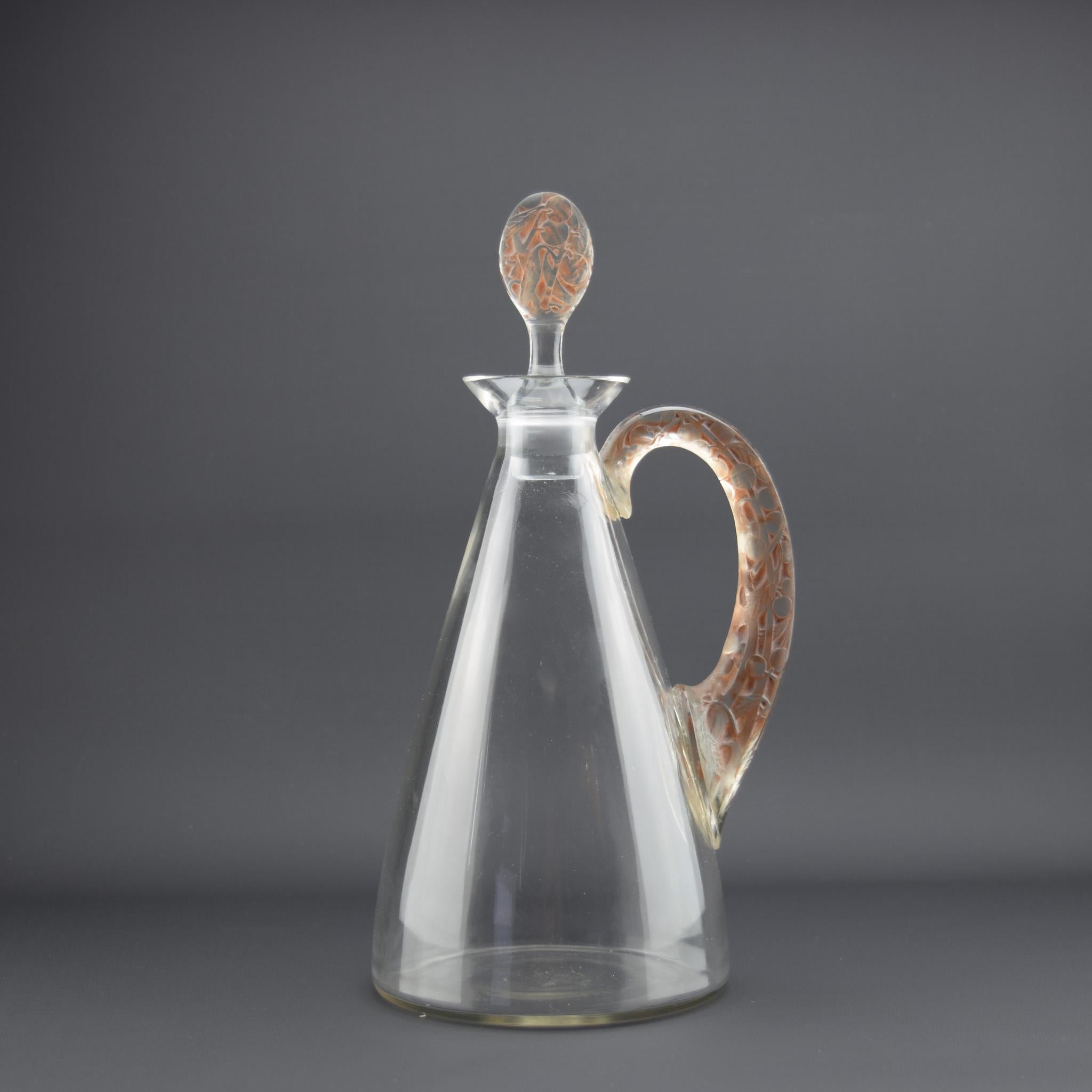 Carafe à décanter Prunelles de René Lalique

Poignée teintée en sépia, moulée avec des prunelles et du feuillage.

Gravé à la base R Lalique également numéroté avec le même correspondant que le bouchon.

L'état est très bon et ne présente aucun