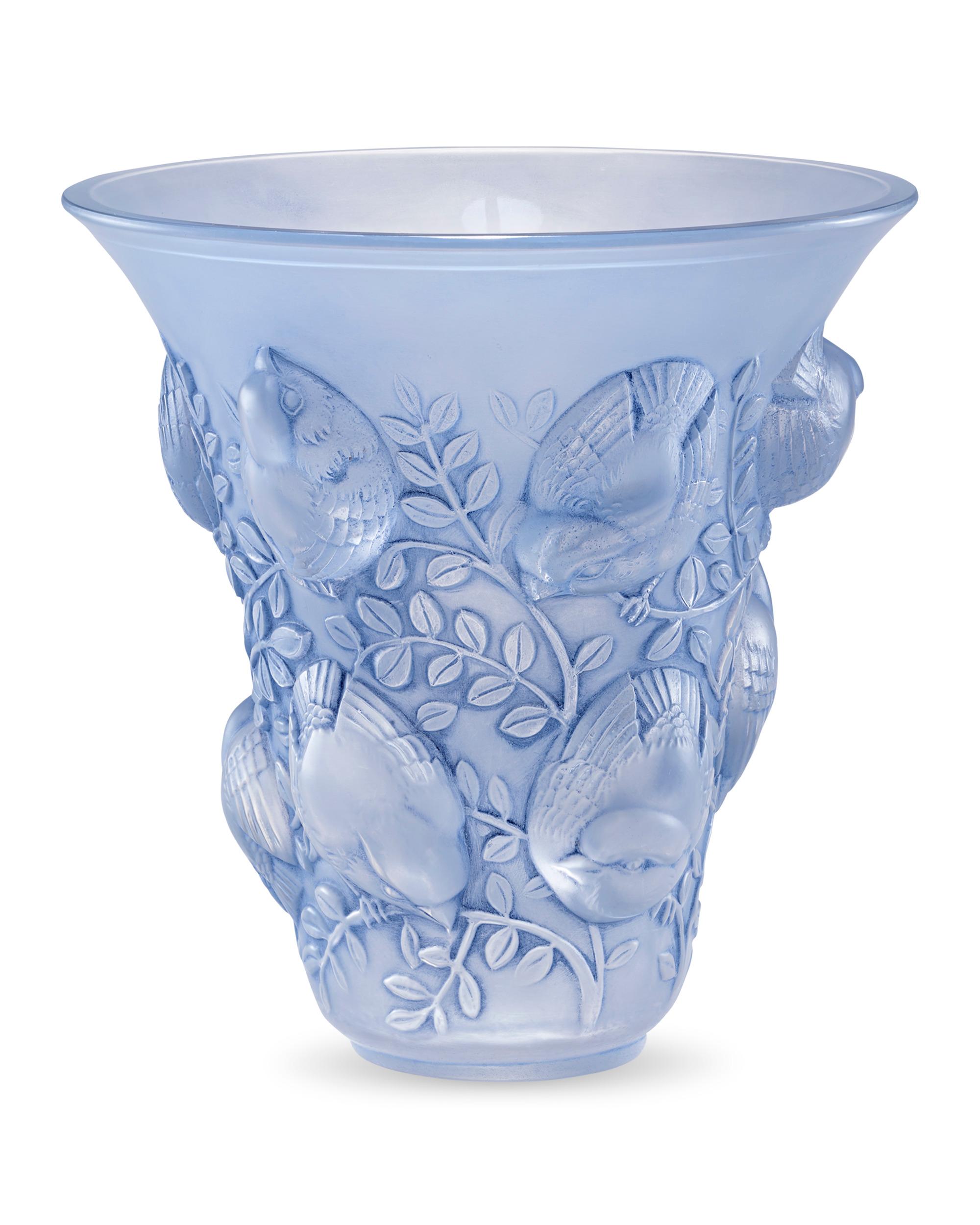 This elegant and opalescent trumpet-shaped vase comes from French glassmaker René Lalique. This motif, known as the Saint-Francois design, includes an animated scene of high-relief songbirds perched upon low-relief foliage. This vessel highlights