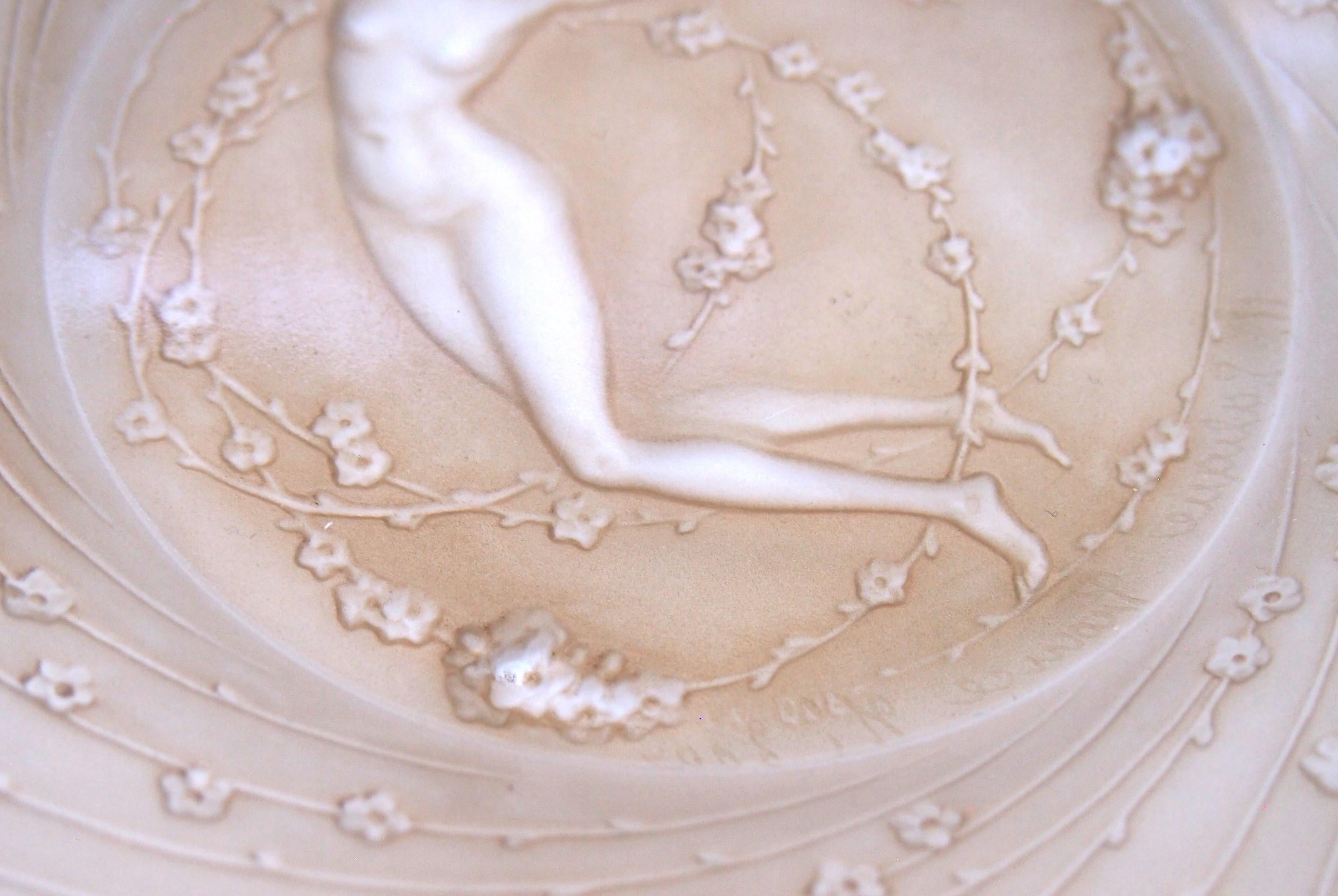 An iconic and rare Rene Lalique 'Une Figurine et Fleur' small pate with original sepia staining -one of his earliest designed plates and it shows one of his most iconic images; a beautiful naked lady with a 1920s haircut, dancing amongst long fronds