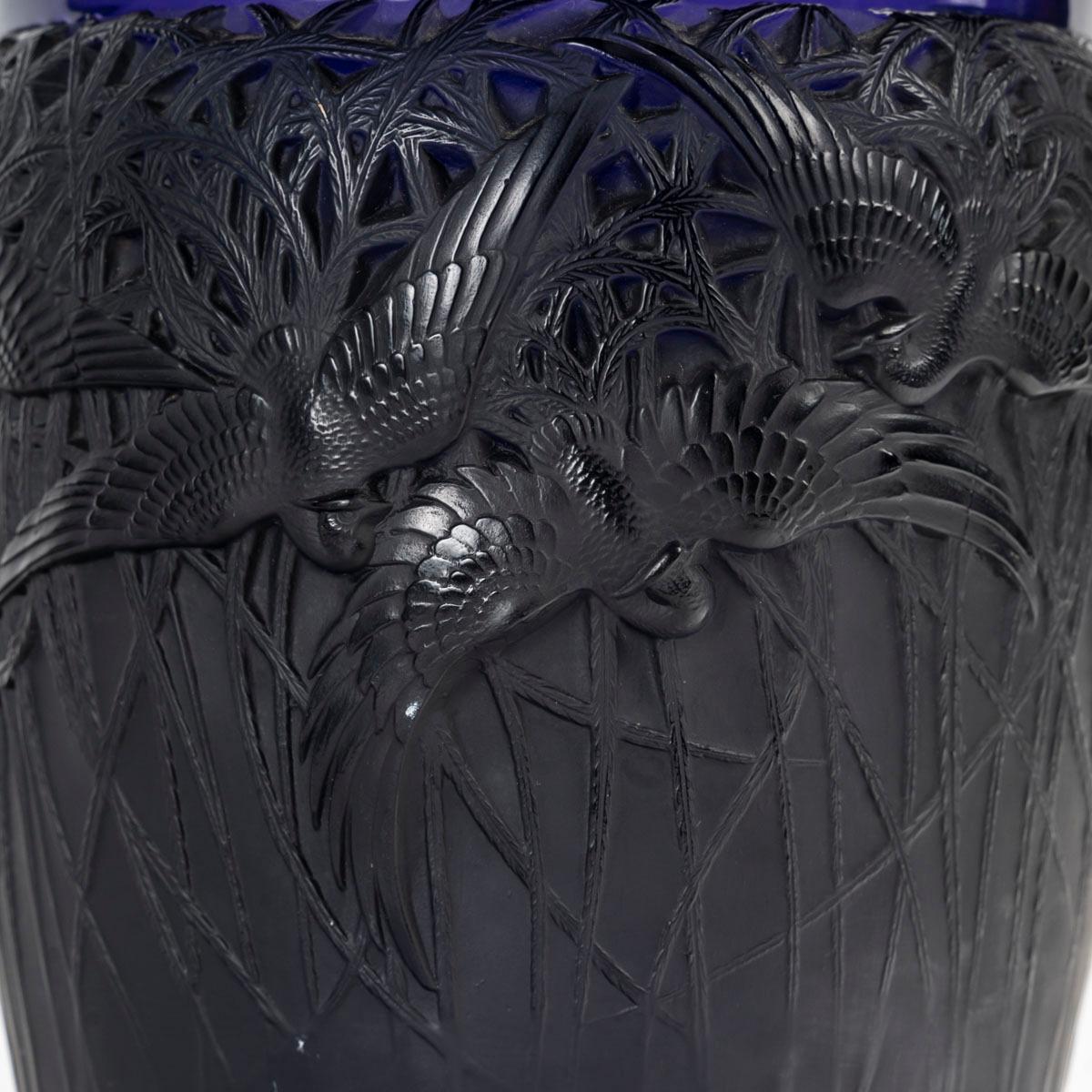 René Lalique ,Vaso 'Aigrettes' in vetro stampato.
 modello creato nel 1926. 
Firmato R Lalique in intaglio.
Condizioni perfette.
Colore viola scuro.                                      
Altezza: 25 cm 
Félix Marcilhac, René Lalique - Catalogue