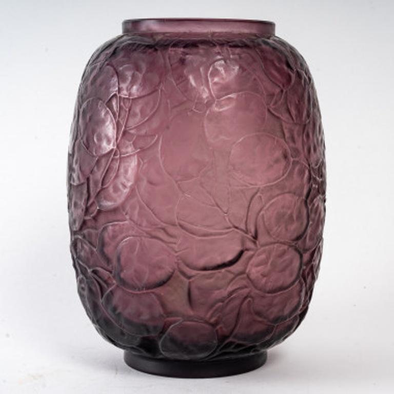 Pressed glass vase with amethyst tintHeight 23 cmFélix Marcilhac, René Lalique - Catalogue Raisonné de l'Œuvre de Verre, Les Éditions de l'Amateur, Paris, 2004, N°897

More photos on request.Delivery worldwide with estimate on request.