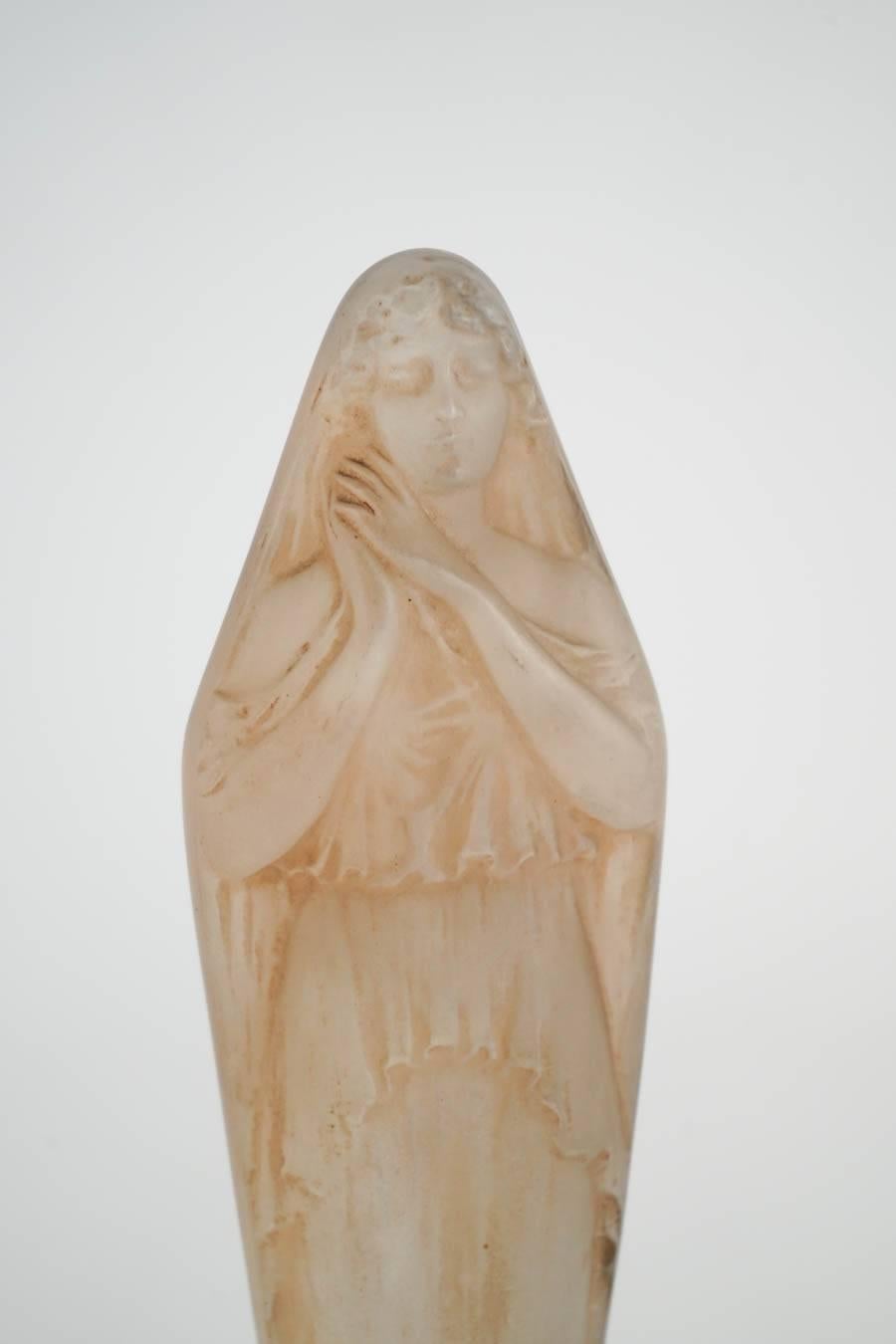 Molded pressed glass
Standing female figure with hands clasped on her right below her chin Model: 828 created, circa 1919.