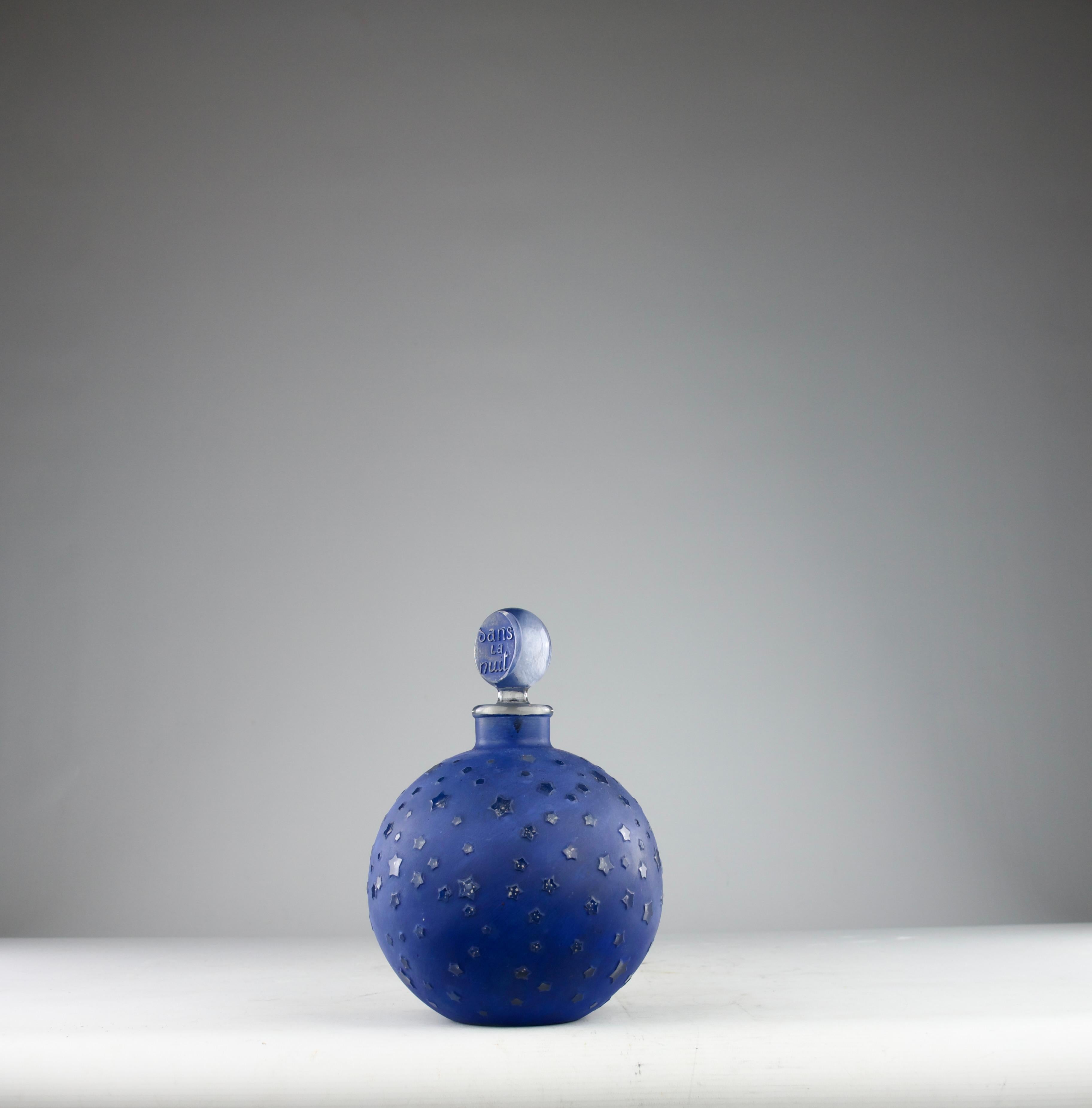 An icon of Art Deco design in its largest size by René Lalique for the legendary House of Worth. Dans la Nuit—“In the Night”—captures the poetry of the cosmos in sculpted glass.

Its deep cobalt-blue surface, luminous yet velvety, evokes the