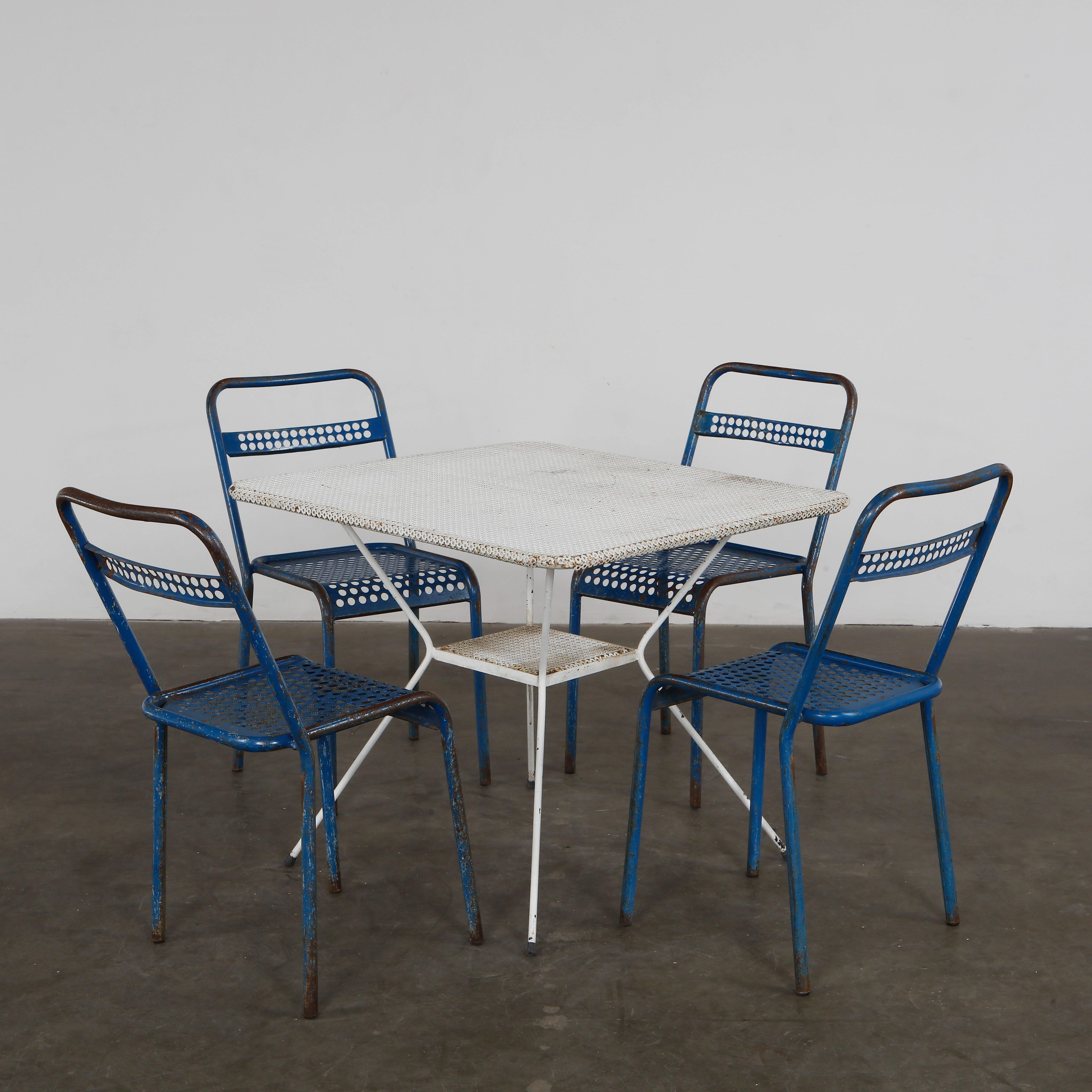 Tavolo in metallo traforato di colore bianco con quattro sedie blu. Fascino retrò, finitura con agenti atmosferici. Sedie: Altezza: 31,5 pollici. Larghezza: 15,5 pollici. Profondità: 19 pollici. Profondità della seduta: 15 pollici. Altezza della