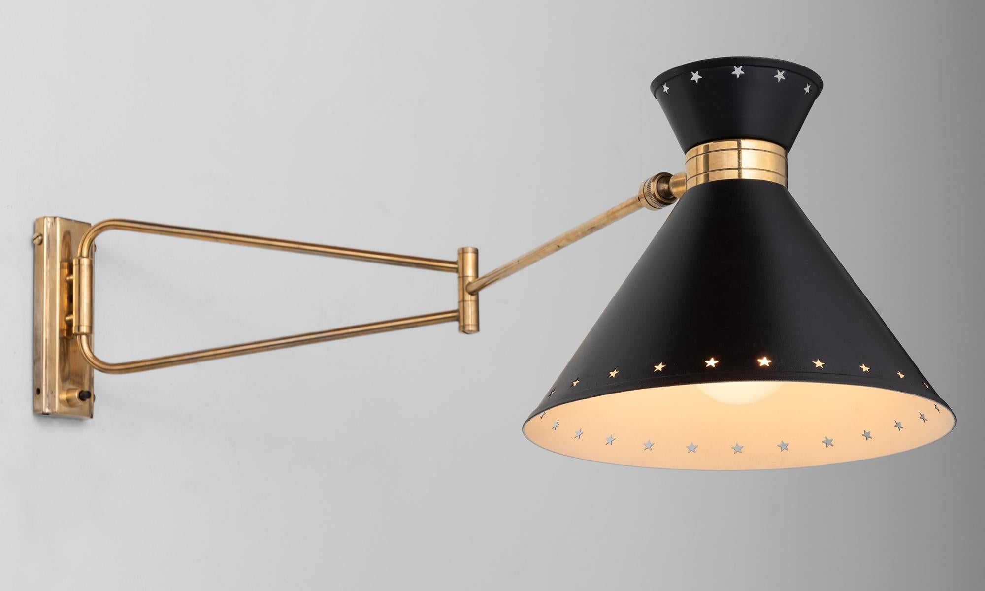 Rene Mathieu swing arm sconce, France, circa 1950.

Brass-plated metal hardware and perforated black shade with swing arm and switch on backplate. Produced by Lunel.