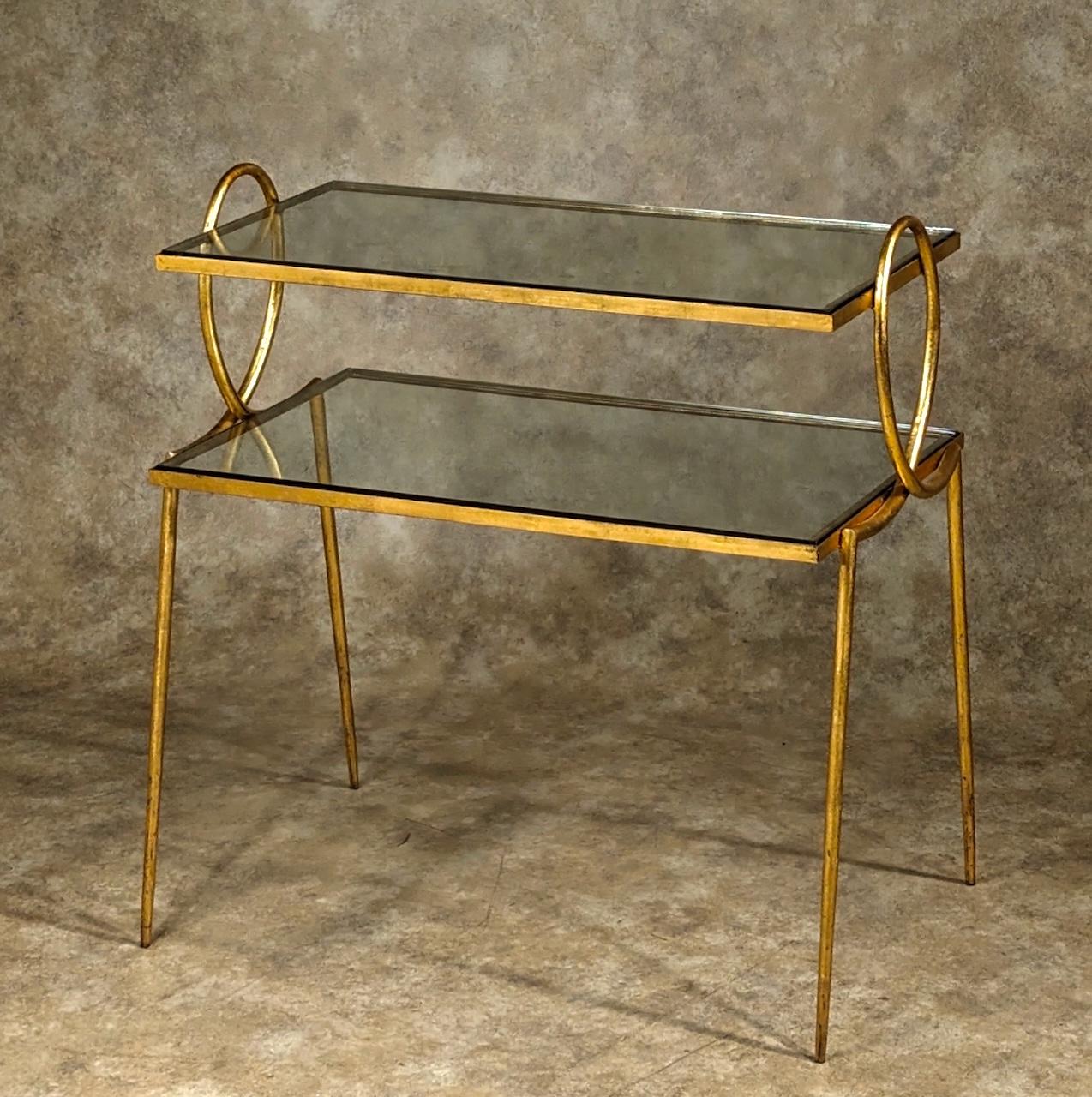 French Forties Art Deco two-tiered table by Rene Prou, 1949, in gilt forged iron with glass insets. This model is pictured in Maison Francaise, November 1949. Please see photos. 28.5” wide x 16.5” deep x 30” high to top of loop. 28” high to top