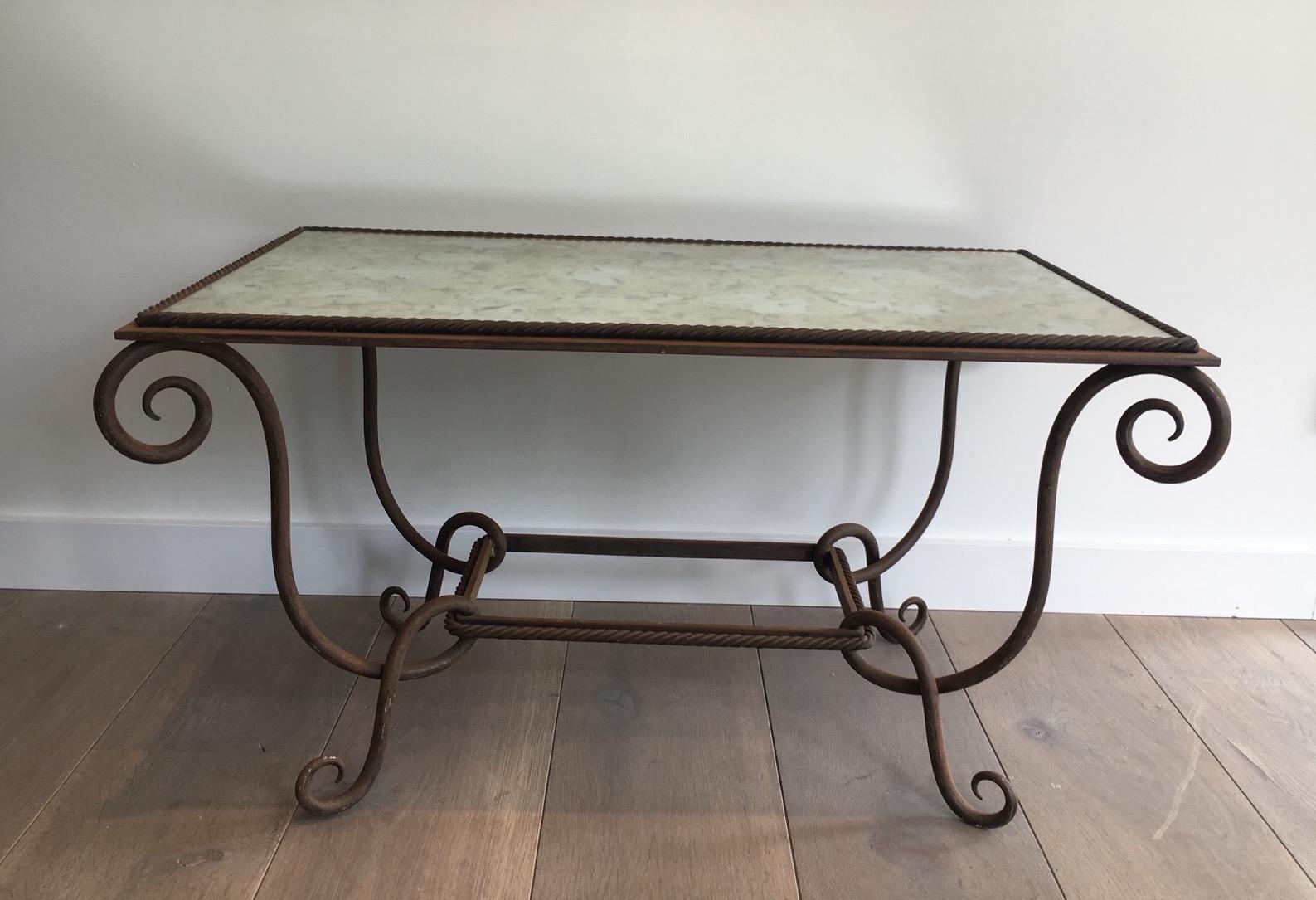 This unusual coffee table from 1940s is made of wrought and hammered iron. It has a faux-antique mirror on top which is new and has been remade in the style of the old mercury mirrors. This coffee table is a French work typical from the famous