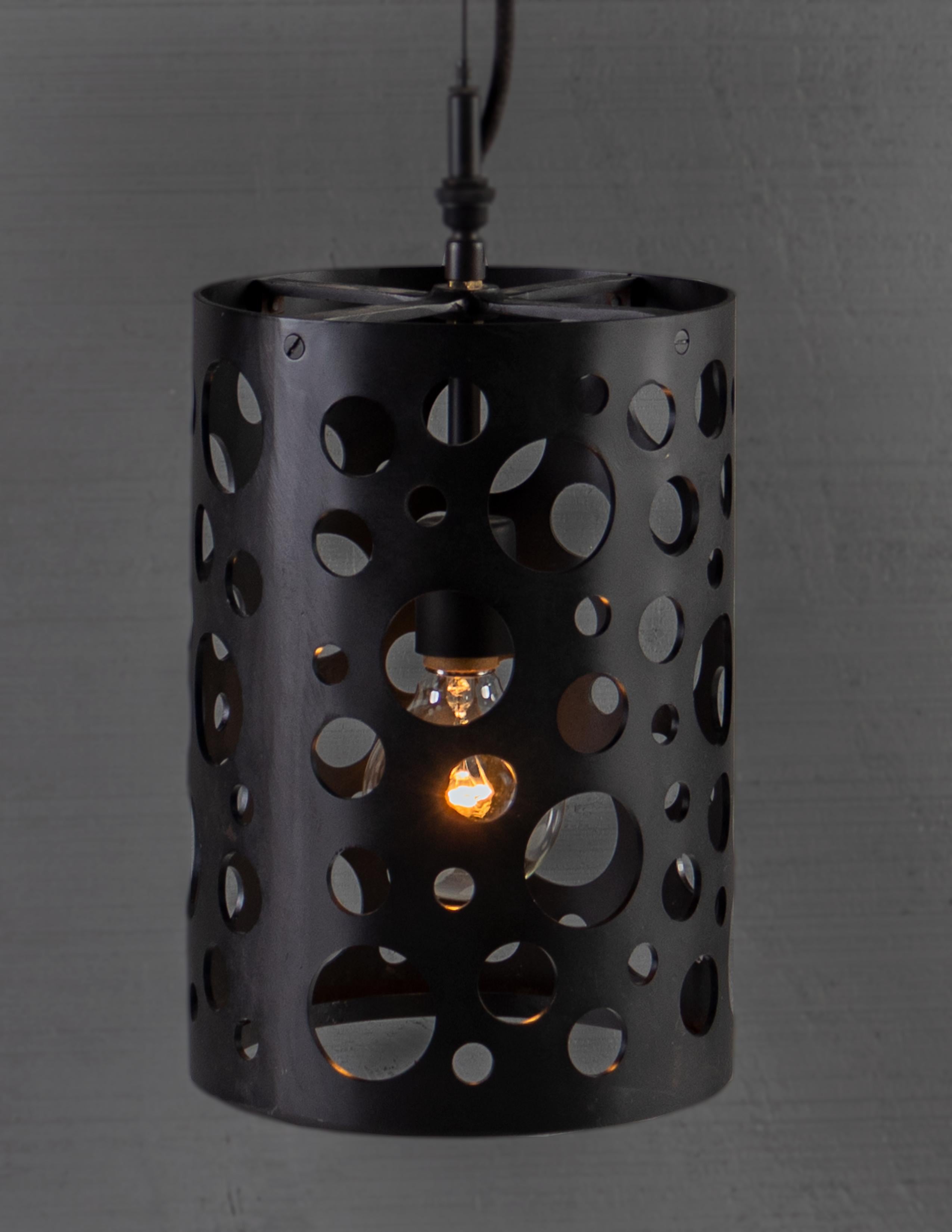 Punched steel, random circles. Perforated circular cut outs on cylindrical body pendant light. 

Bulb 1x medium base 75 watt incandescent. 

Handcrafted in Italy. Sold exclusively at Brendan Bass.

Minimum hanging height: N/A
Maximum hanging height