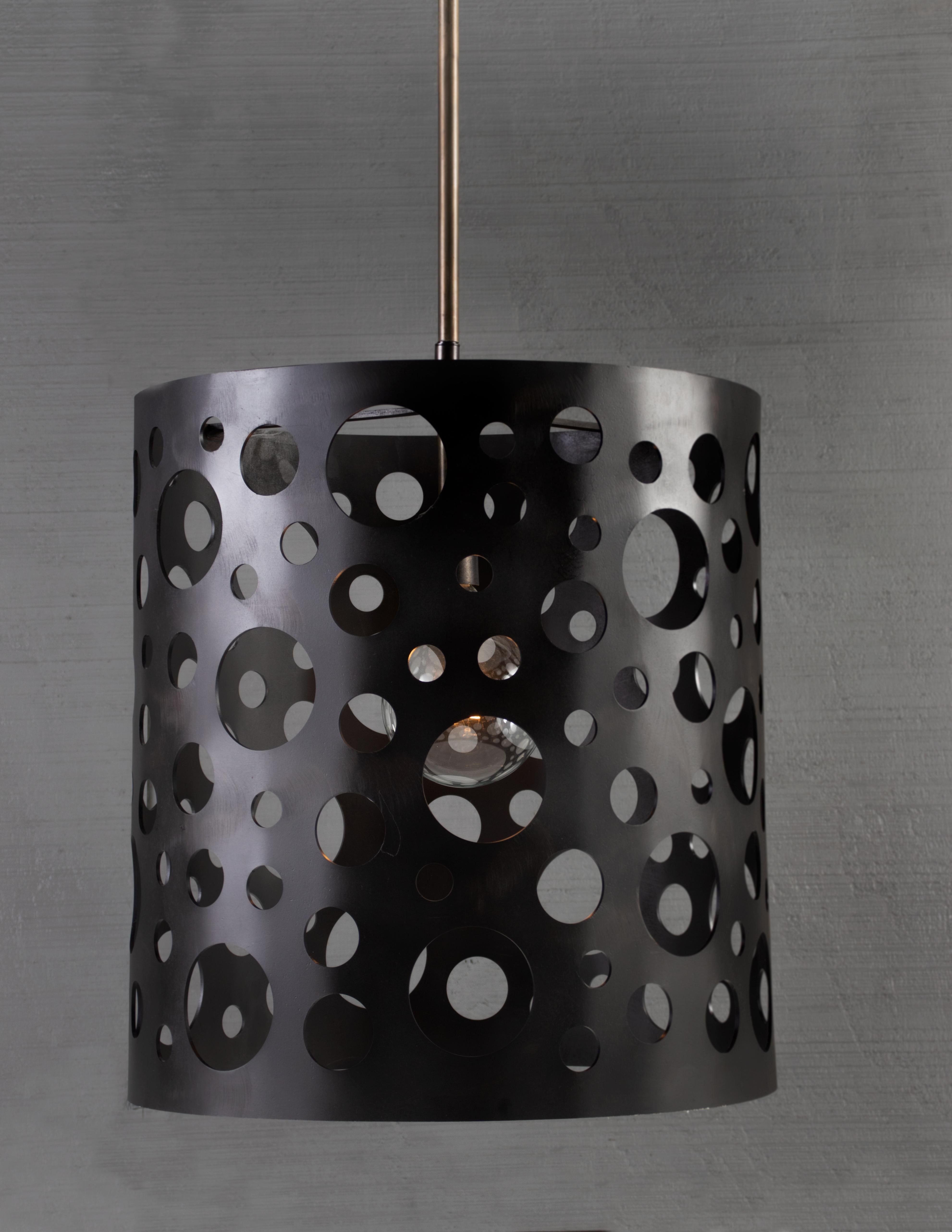 Punched steel, random circles. Patinated steel cylindrical body with random circles cut out of pendant light.  

Bulb 1x medium base 100 watt incandescent.

Handcrafted in Italy. Sold exclusively at Brendan Bass.

Minimum hanging height: N/A
Maximum