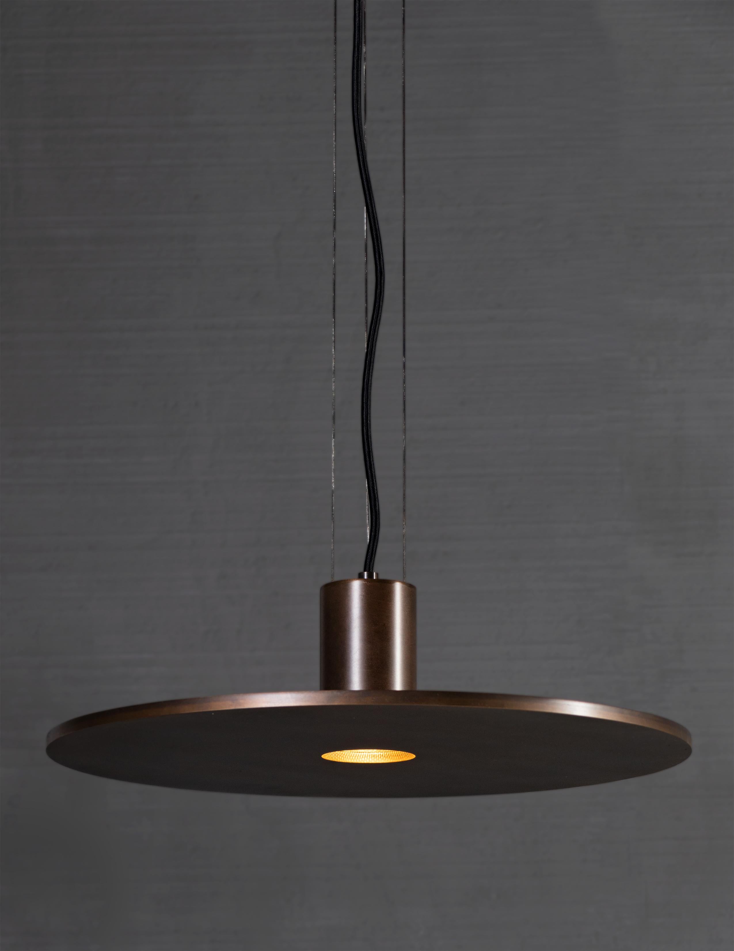 Patinated brass disc light. Cable suspension 

Bulb 1 medium base 60 watt incandescent

Handcrafted in Italy.

Measures: Minimum hanging height: N/A
Maximum hanging height: 72