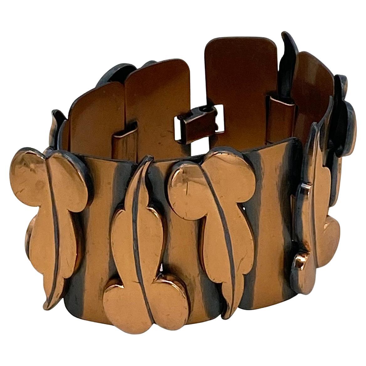 This is a 1950s Renoir of California copper bracelet. Nine panels link with eight stylized leaves. The artificially added dark patina gives greater visual interest. It is signed Renoir on the fold back clasp.  

