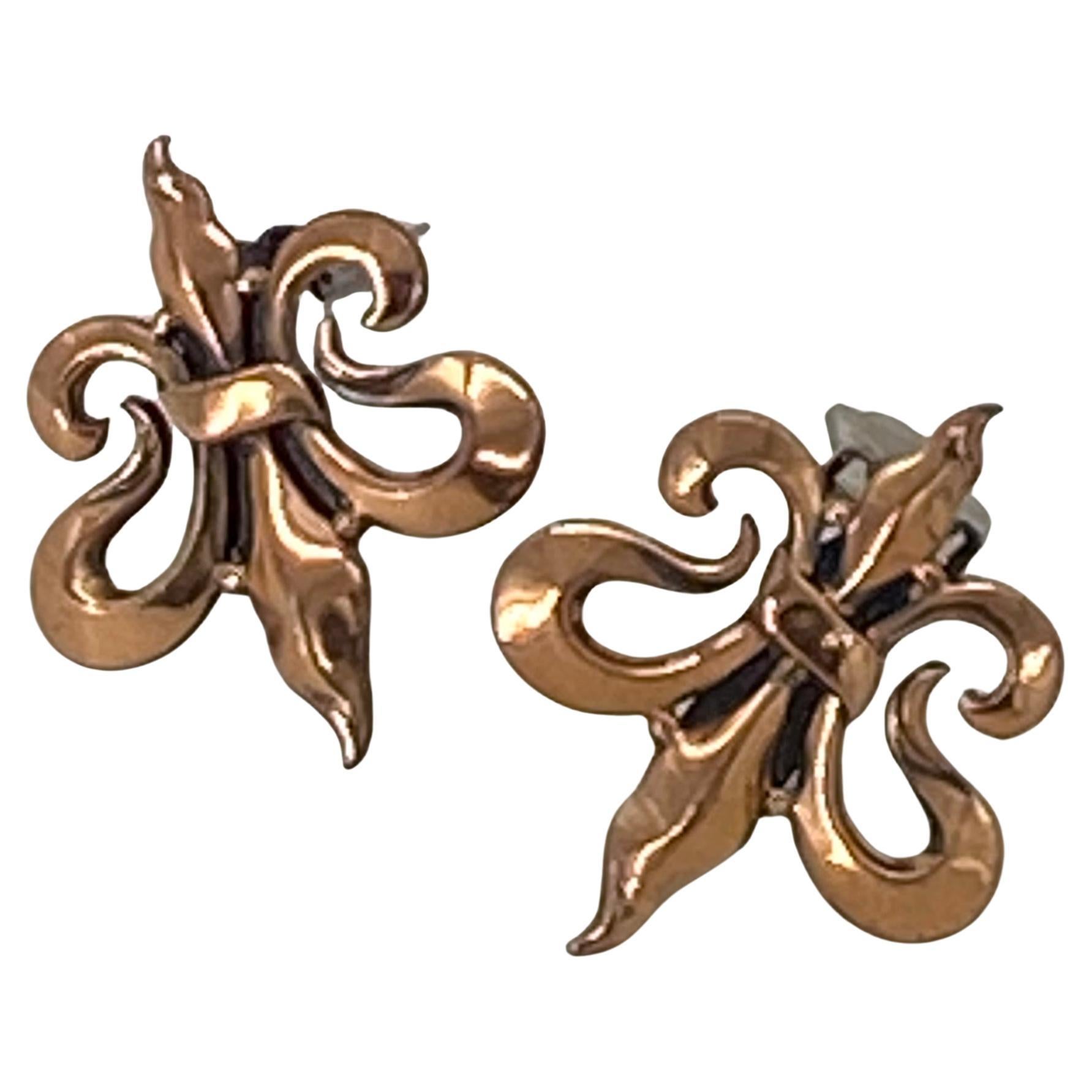 This is a pair of Fleur de Lis pattern copper clip-on earrings with artificially added dark patina for greater visual interest. Each is signed Renoir on the clip back.  

