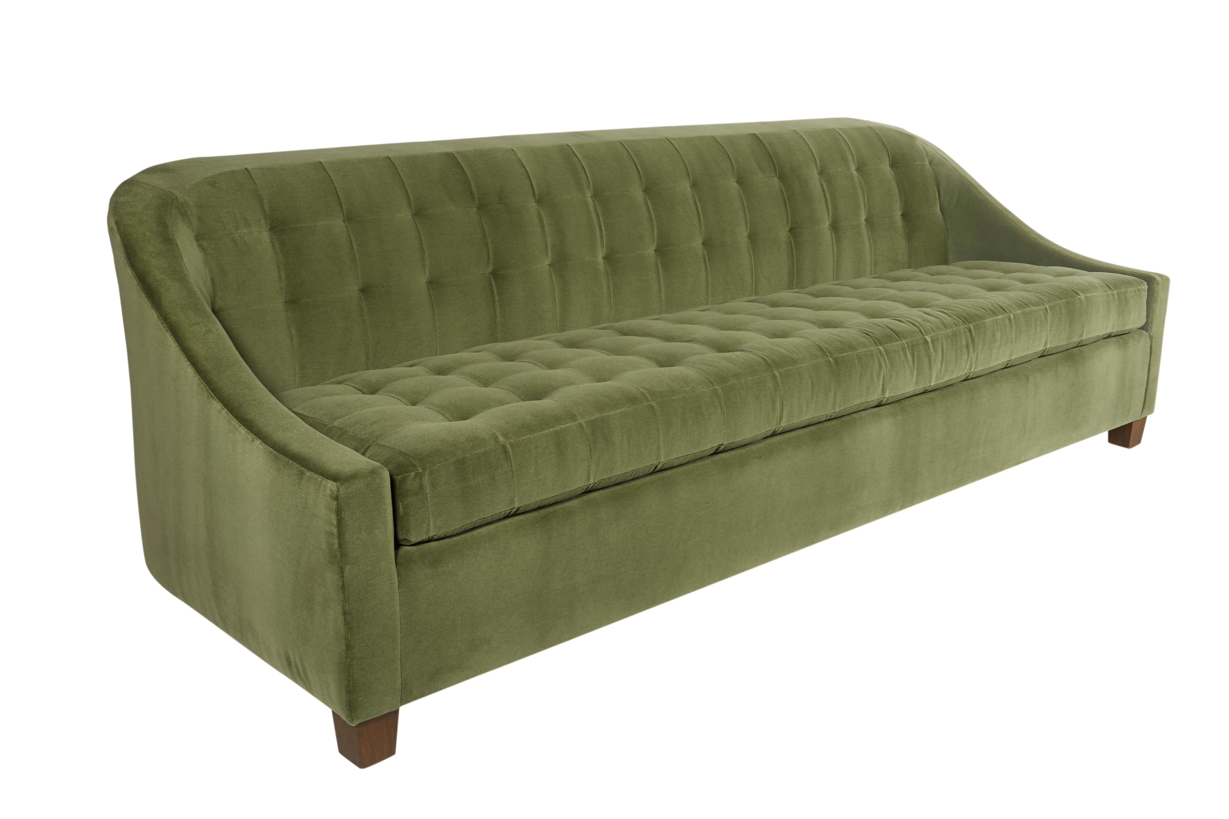 Sloped, low arm sofa featuring blind, recessed tufting on both back and bench seat cushion. The Renwick Sofa frame is constructed using solid maple wood with 50 / 50 down feather filled cushions. Four finishes available for sofa legs. Available in