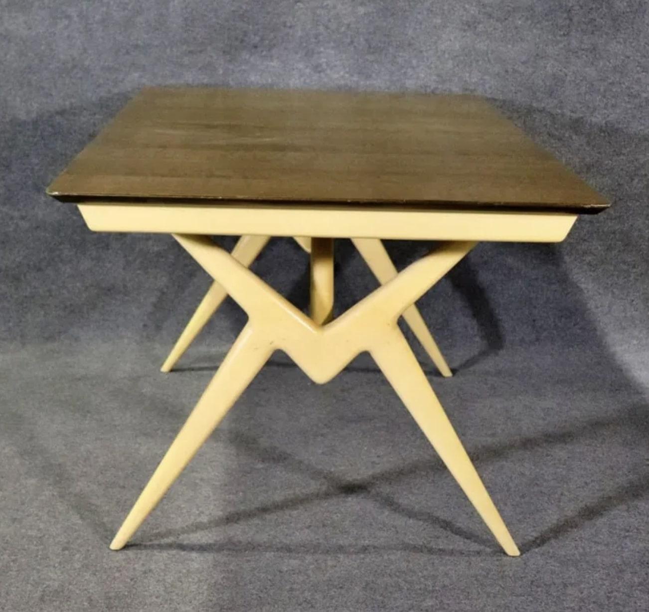 Cette table moderne du milieu du siècle est une pièce de choix pour votre salle à manger. Design/One de Renzo Rutili, avec des pieds en ciseaux et un magnifique plateau en bois. Deux vantaux de 11 pouces permettent d'ouvrir la table de 60 pouces à