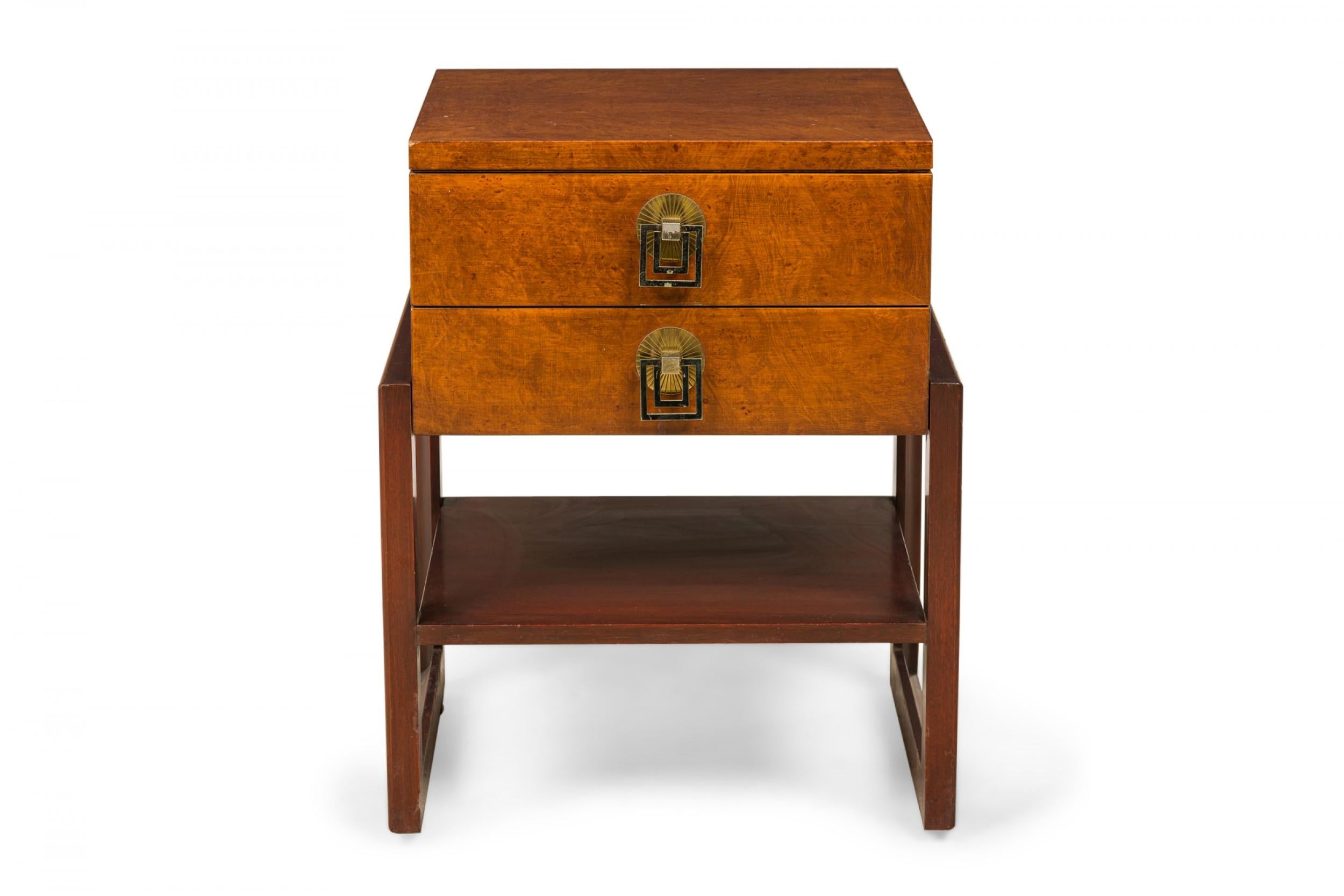 American mid-century nightstand / bedside table comprised of an upper two-drawer chest with burl wood veneer and two polished brass drawer pulls, resting on an open square base with a lower shelf. (Renzo Rutili for Johnson Furniture Company).