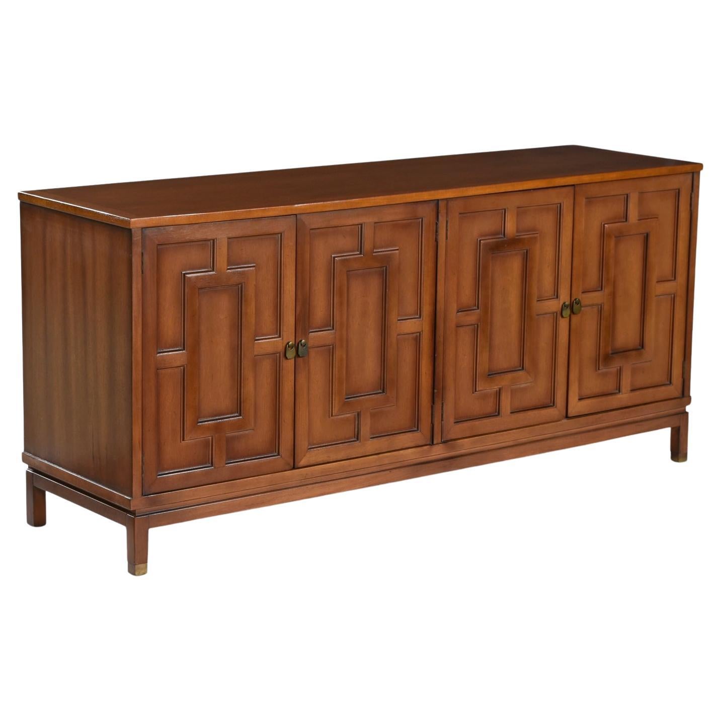 East meets West with this captivating Renzo Rutili style credenza.  Ideal as an entertainment console, dining room sideboard buffet or bedroom dresser. Distinctive brass handle accents and carved fretwork reliefs in the door fronts punctuate this