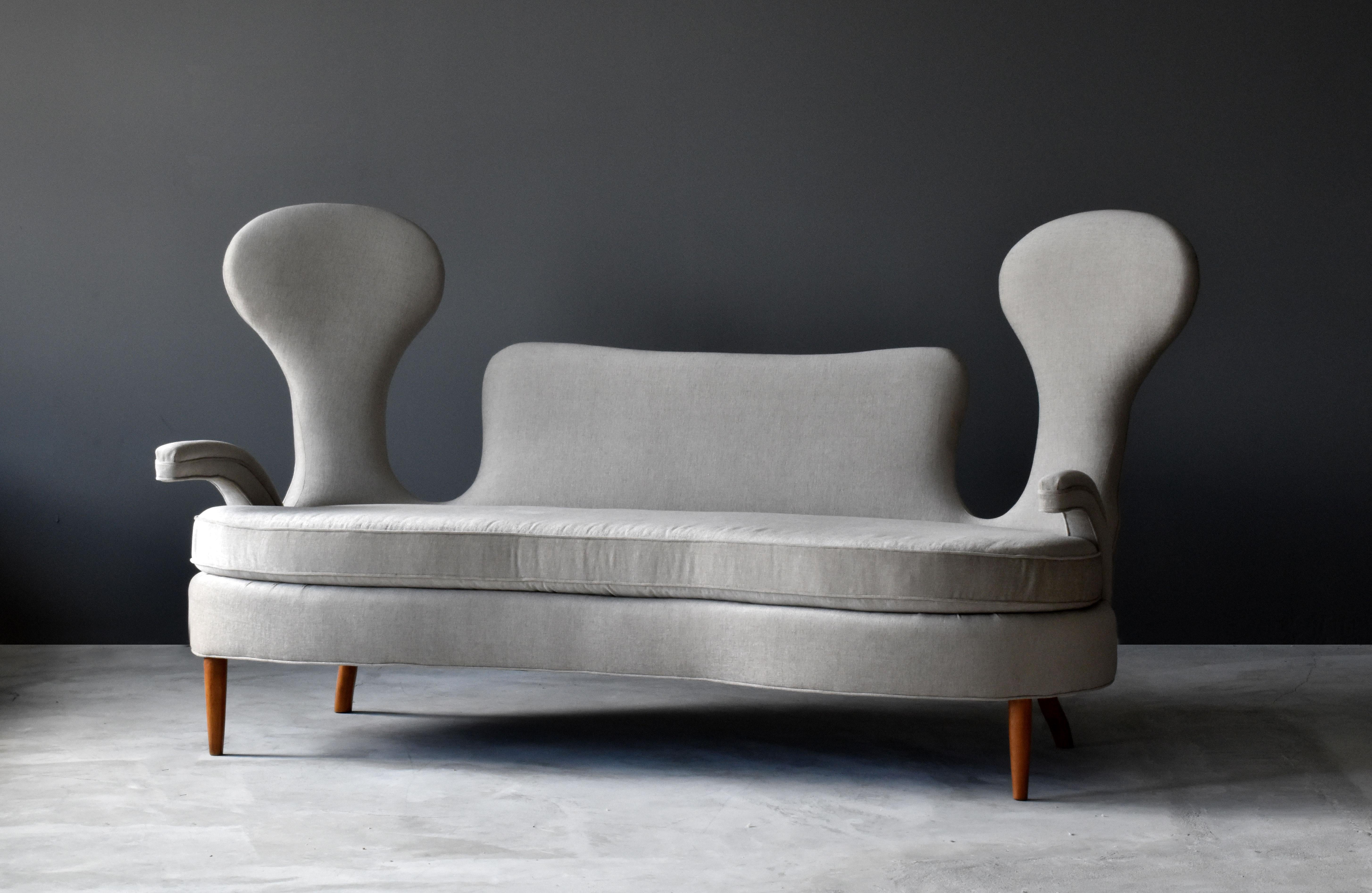 An organic sofa made for hotel San Remo (Rome, Italy), circa 1950, by Italian designer Renzo Zavanella. The design most likely conceived in the latter half of the, 1940s. 

The lively overstuffed form with two high backs provides excellent