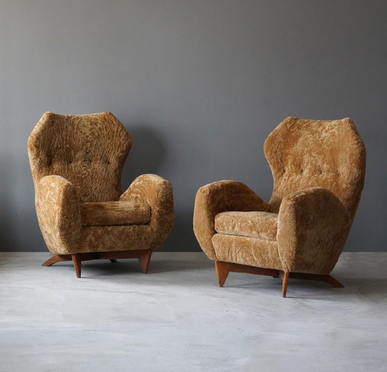 A pair of high-back organic lounge chairs. Designed and produced by Renzo Zavanella for a private client in Bologna, Italy. Reupholstered in brand new sheepskin upholstery. On walnut legs. 

With a certificate of authenticity from the Renzo