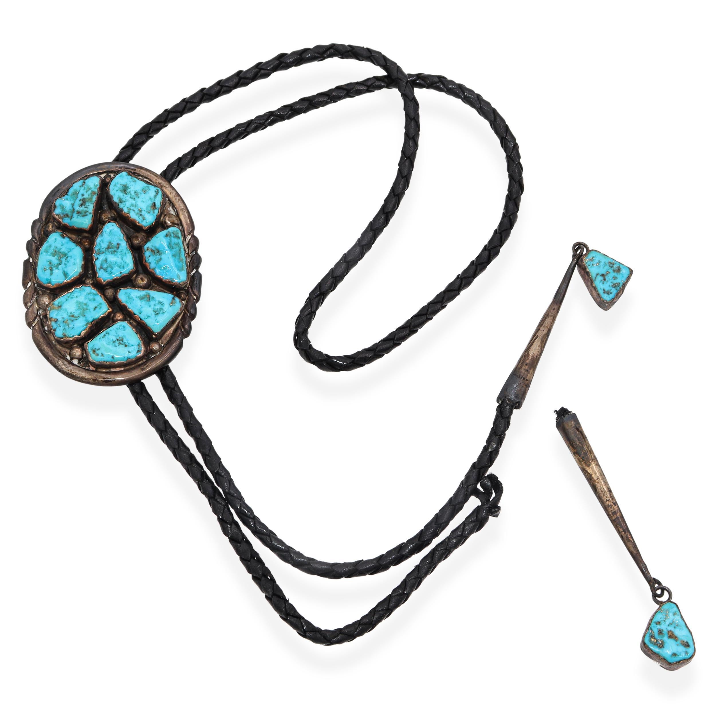 Una bellissima cravatta bolo d'argento Zuni vintage realizzata a mano e firmata EYM, con una slitta ovale intarsiata con un sorprendente gruppo di pietre turchesi naturali. Ogni pezzo di turchese a forma libera è incastonato singolarmente in un