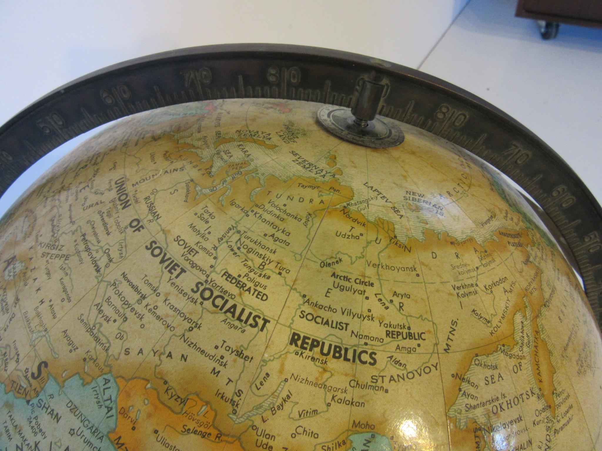A Replogle world globe that turns and spins on a brass square tubed stand in the style of Paul McCobb. Manufactured by the Replogle Globe Company.
