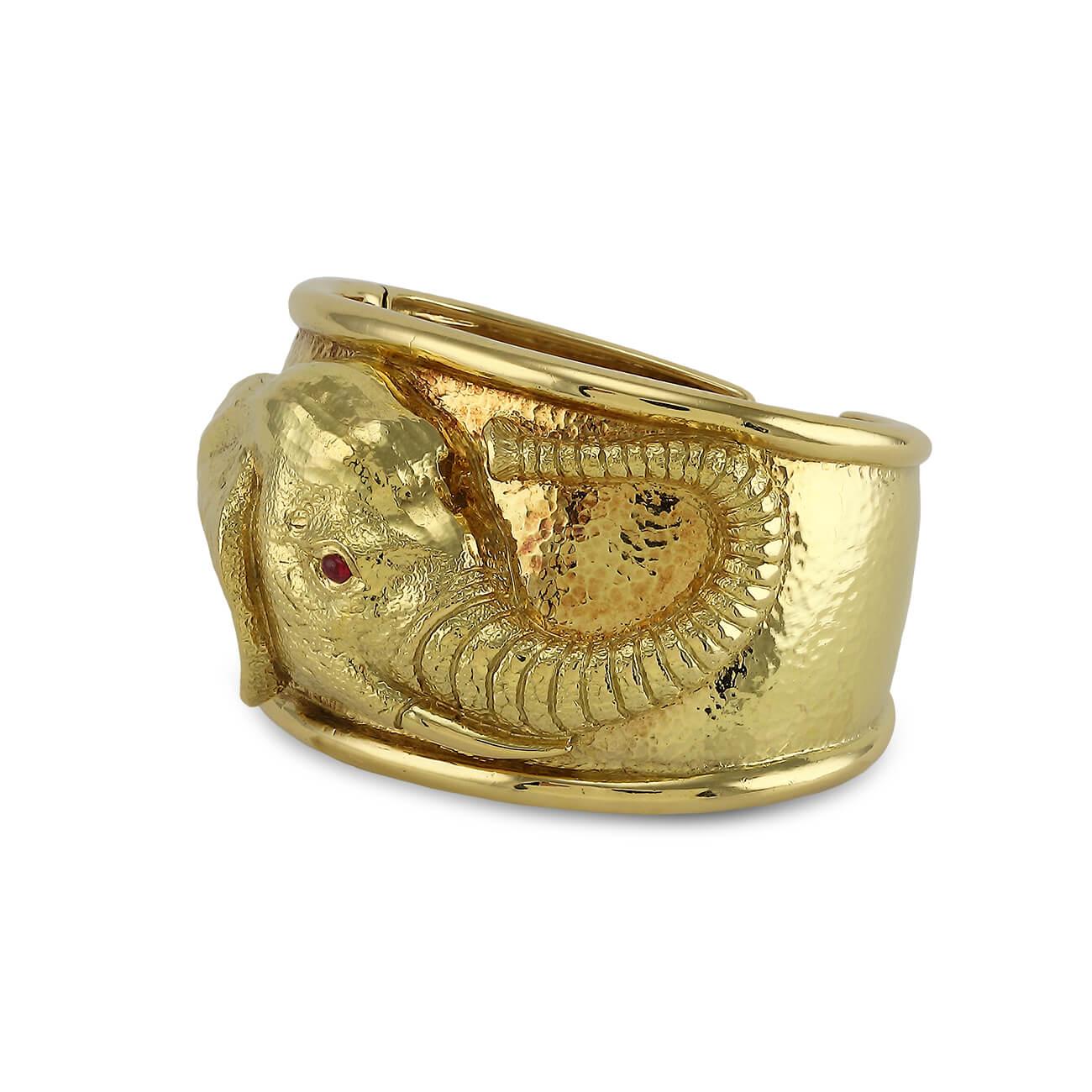 18K Yellow gold elephant cuff by David Webb. The cuff has a repousse elephant head with a ruby eye.

Hammered 18K yellow gold
Cabochon ruby